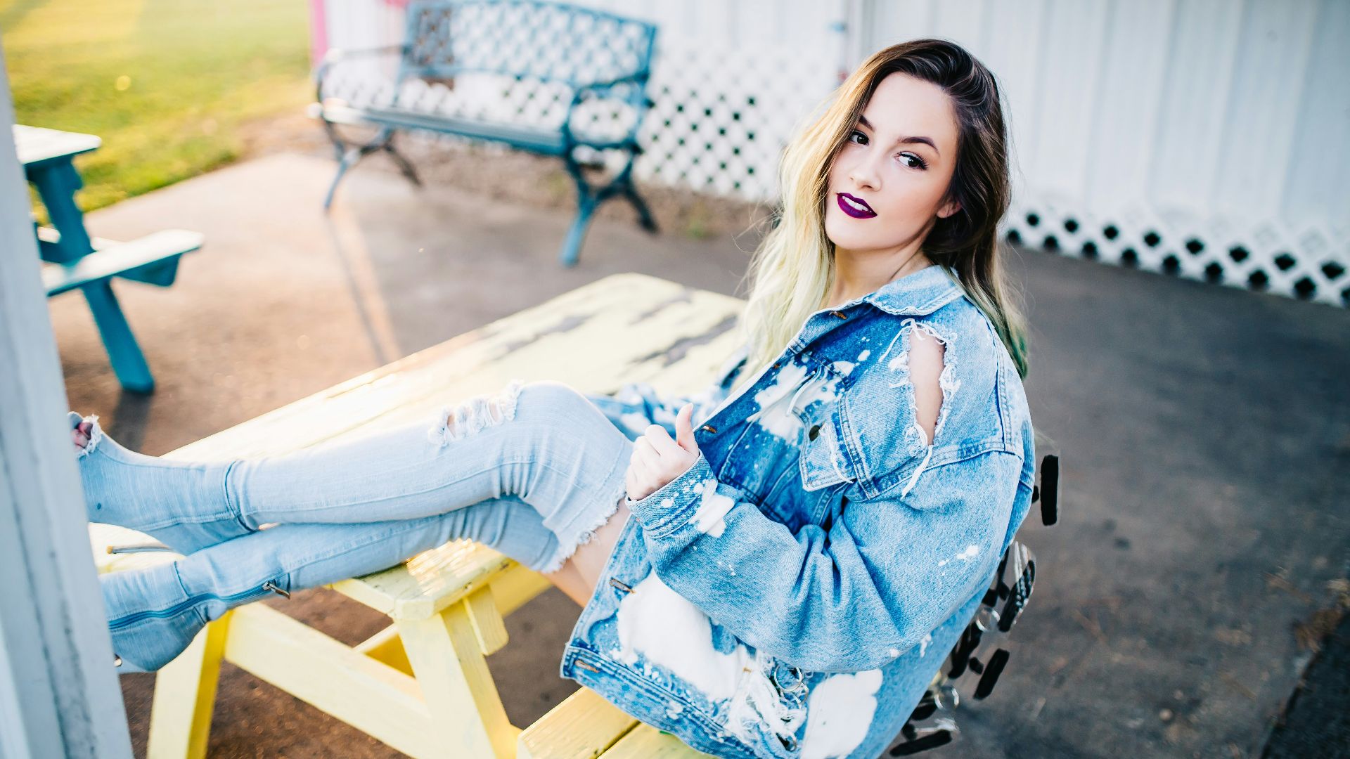 smiling woman sitting on yellow picnic table during daytime