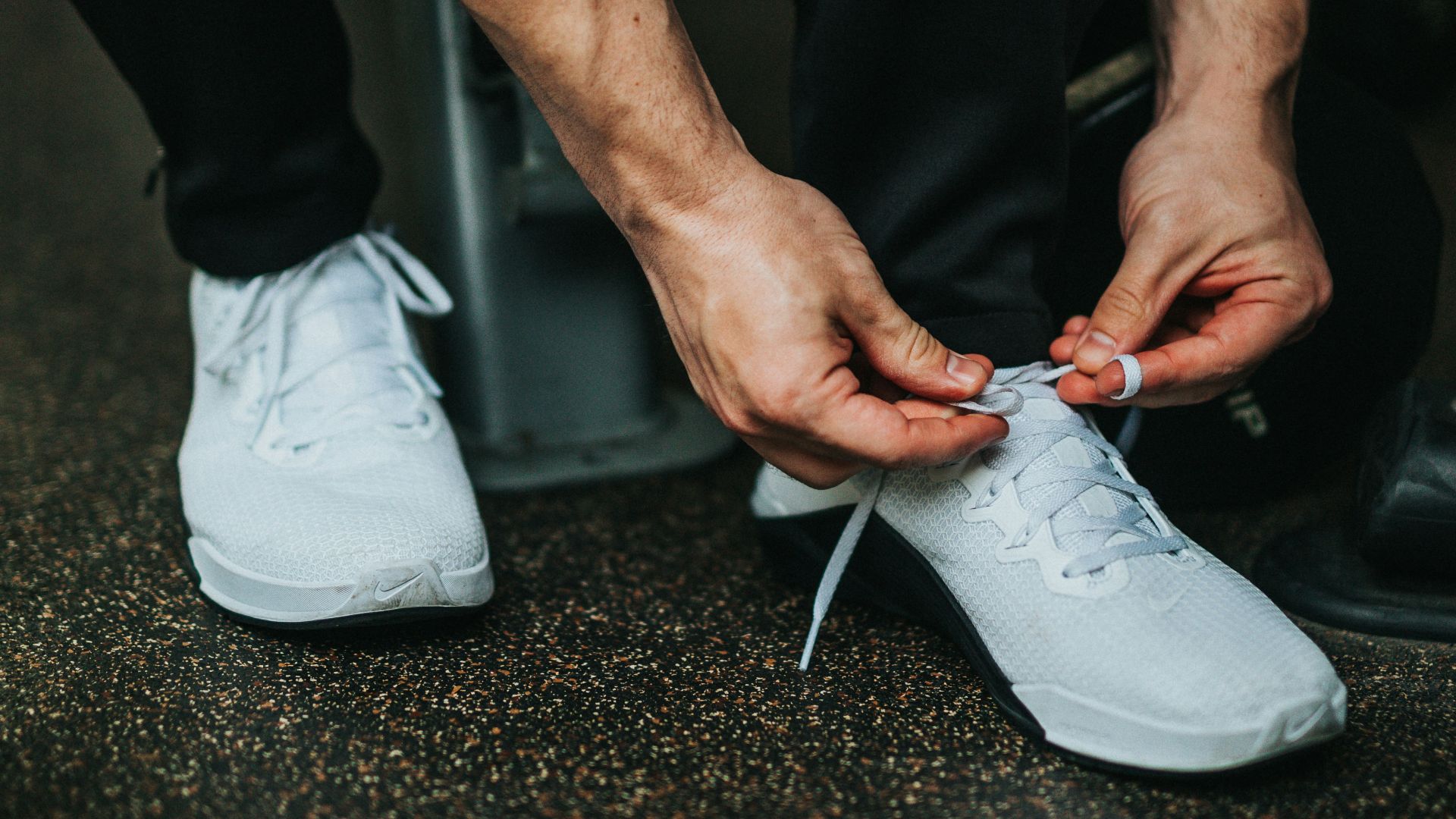 man sitting down while tying shoe lace