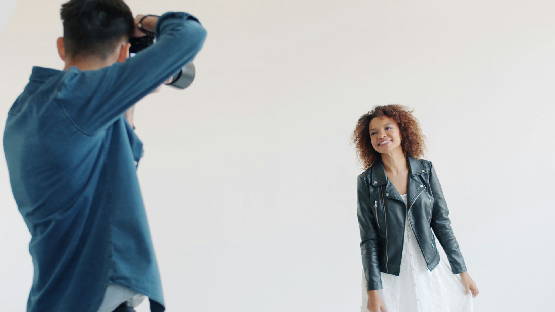 Model poses for photographer in studio setting.