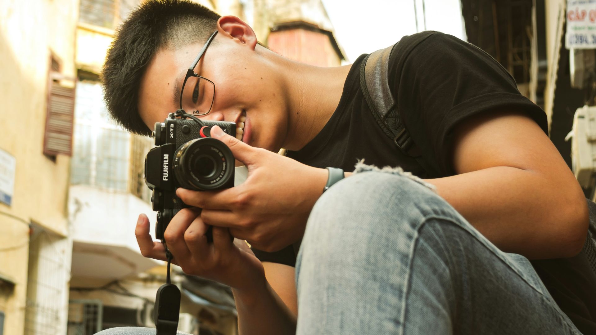 a woman sitting on a stool holding a camera