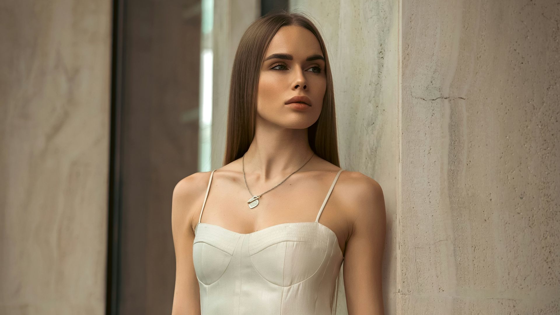 A woman in a white dress poses elegantly.