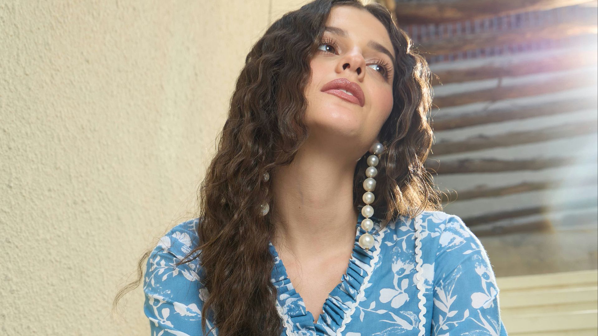 Young woman in blue floral outfit sitting on stairs