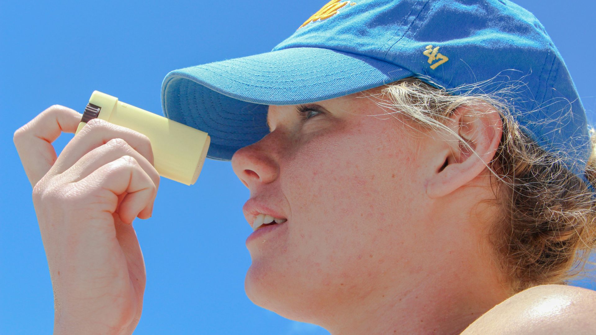 a woman wearing a blue hat looking through a magnifying glass