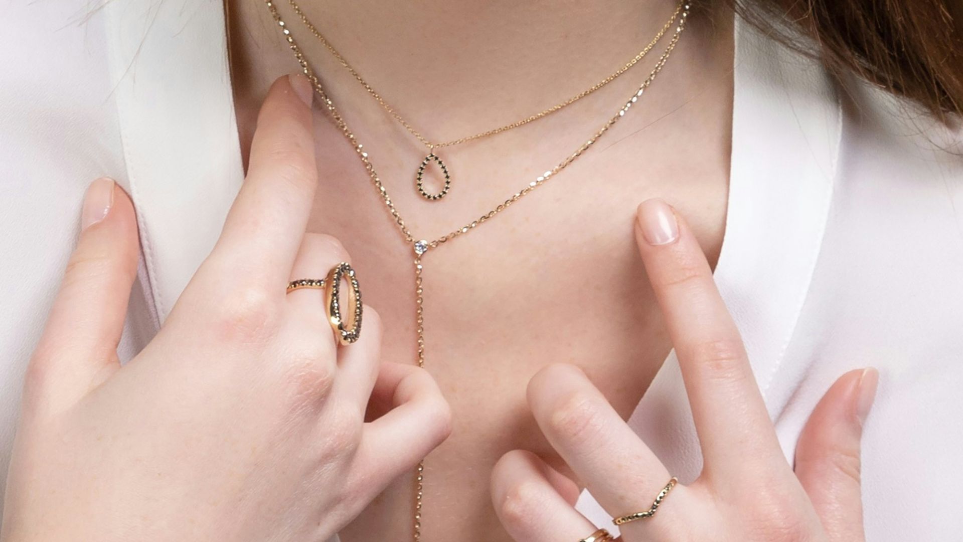 a close up of a person wearing rings and a necklace