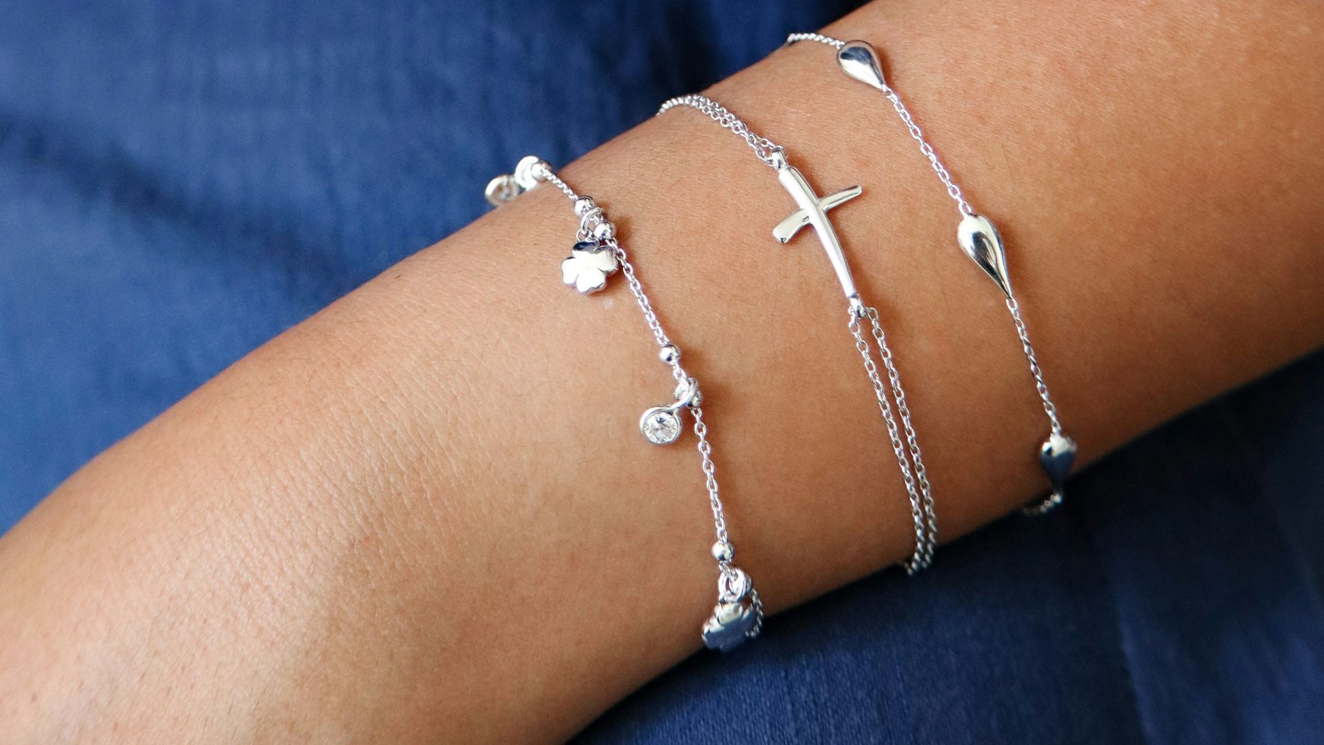Two arms adorned with delicate silver bracelets.