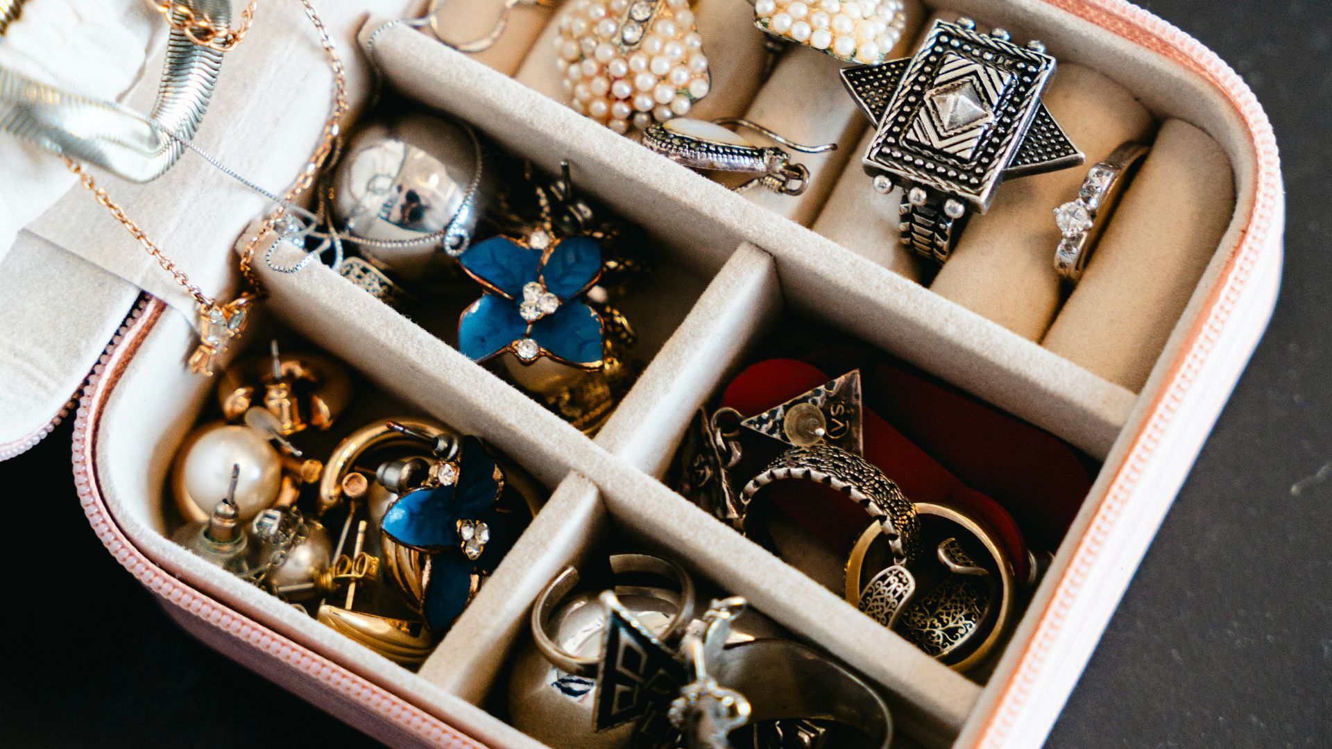 A pink jewelry box filled with necklaces and rings.