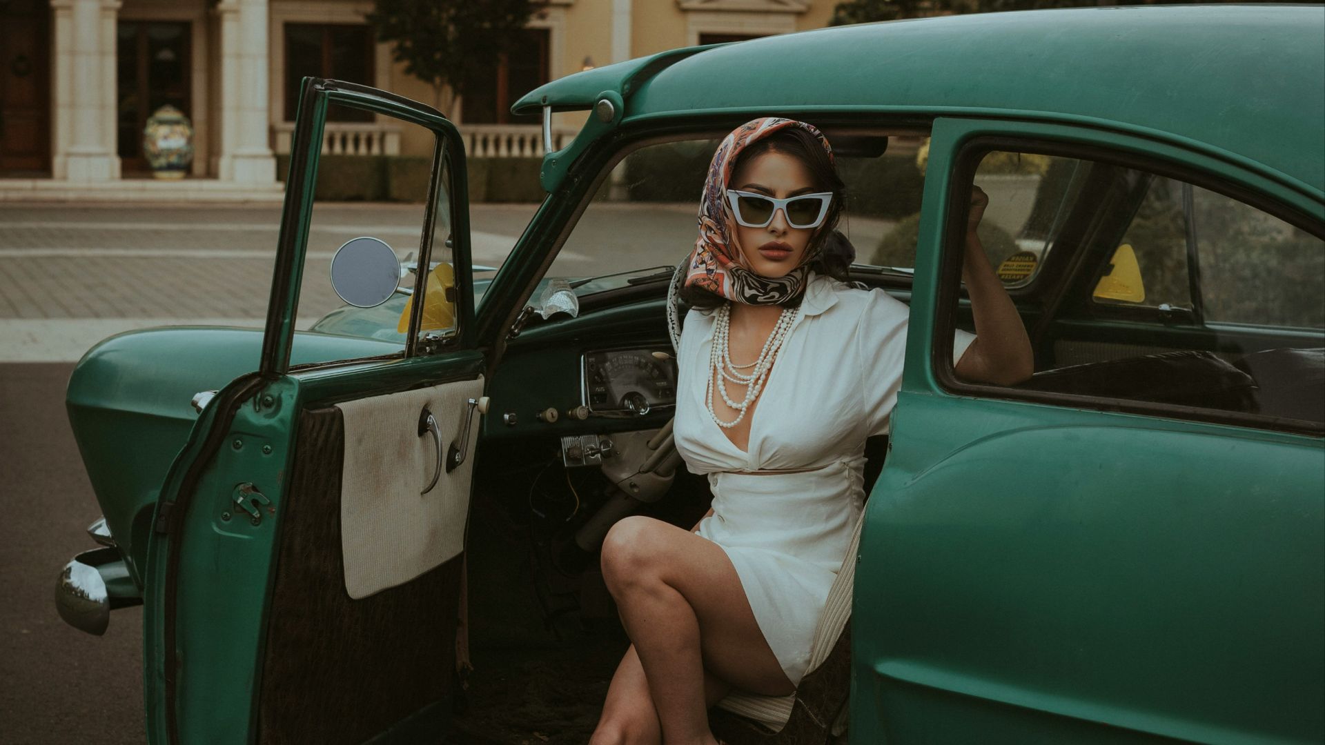 a woman sitting in the back of a green car