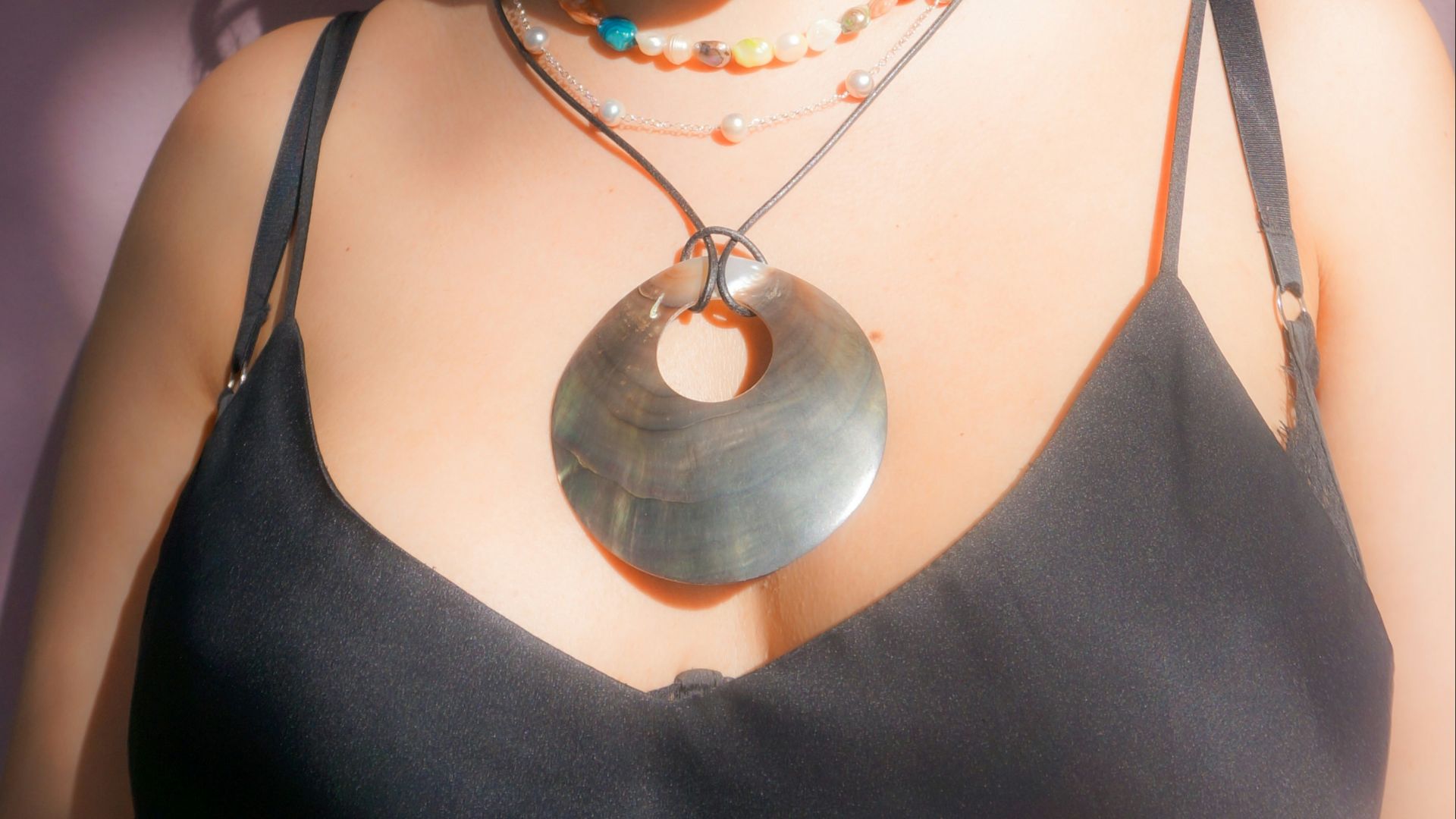 A woman with curly hair and necklaces smiles