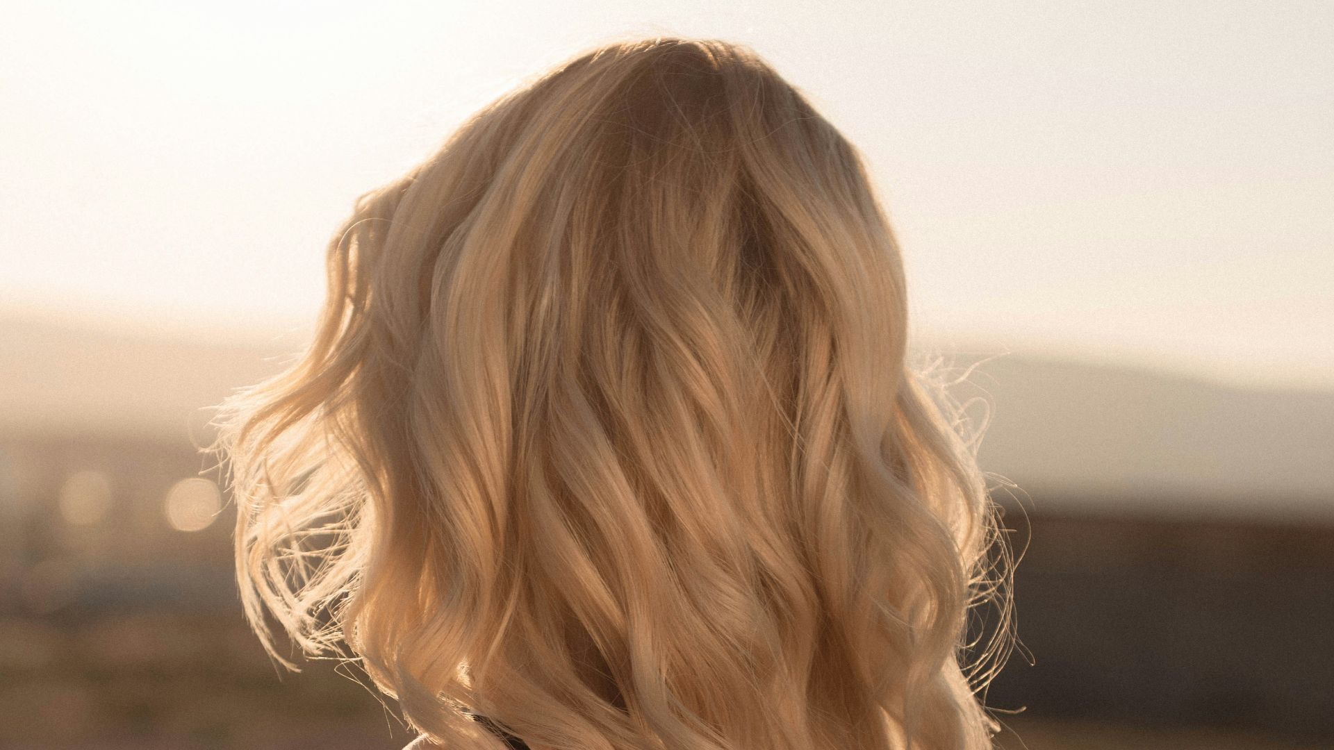 a woman with blonde hair standing in a field