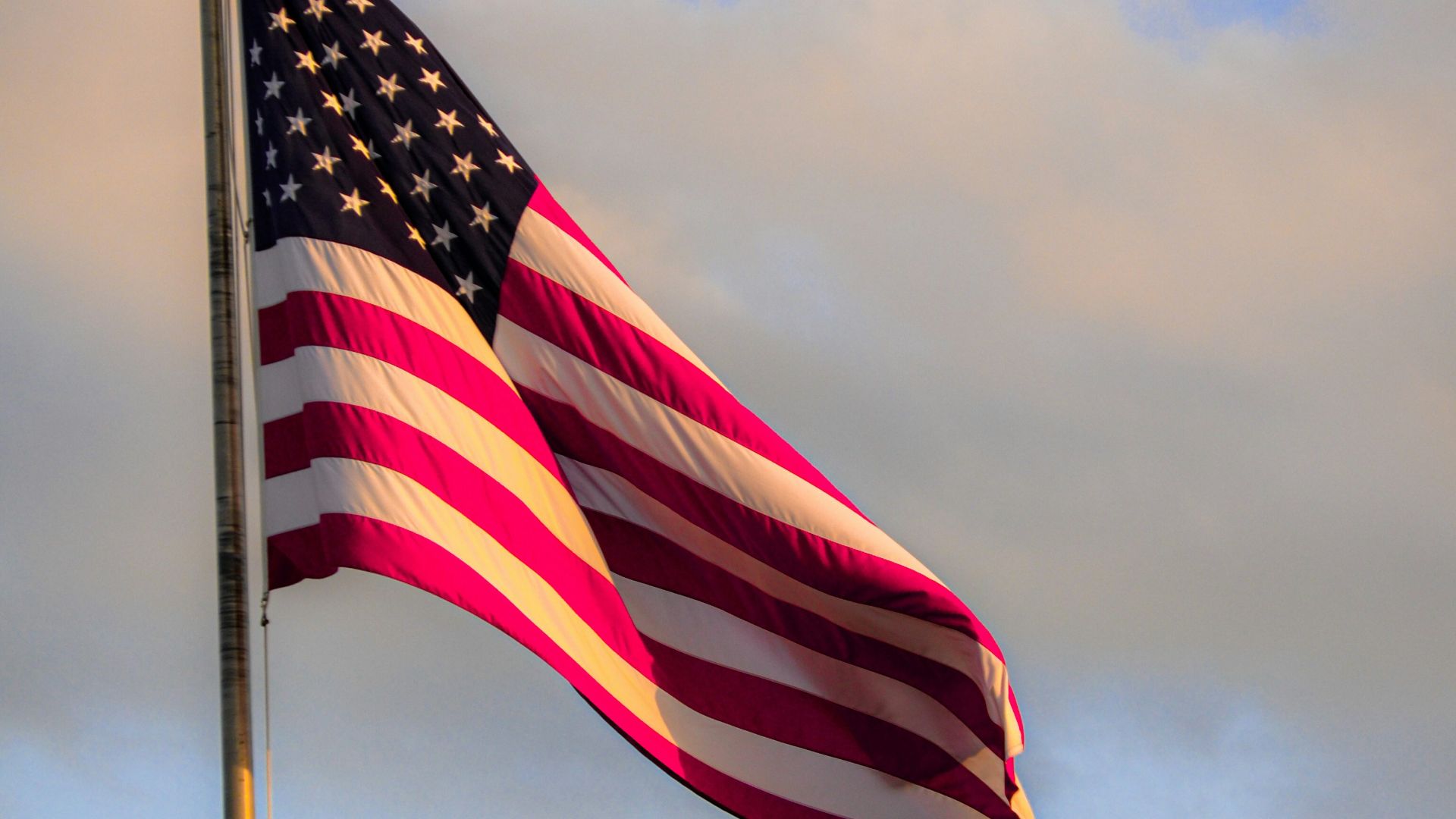 us a flag on flag pole under cloudy sky during daytime