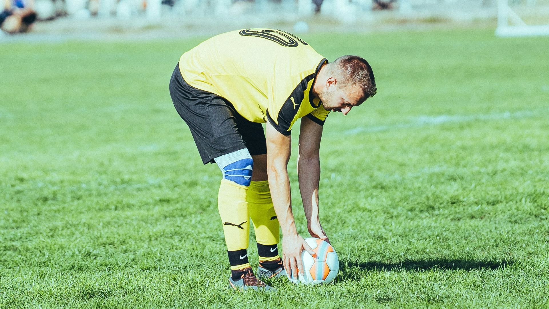 man in yellow shirt and black shorts playing soccer during daytime