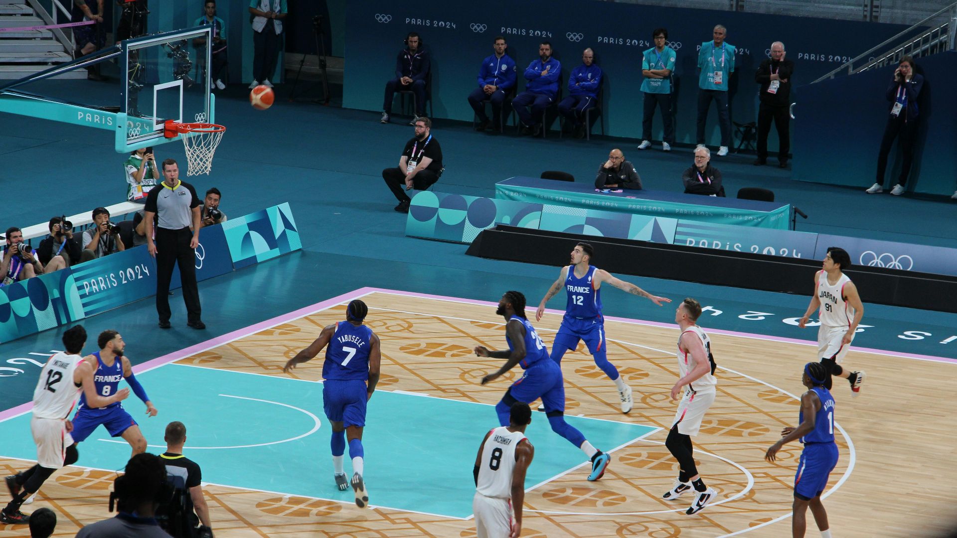 Basketball players compete on a court during a game.