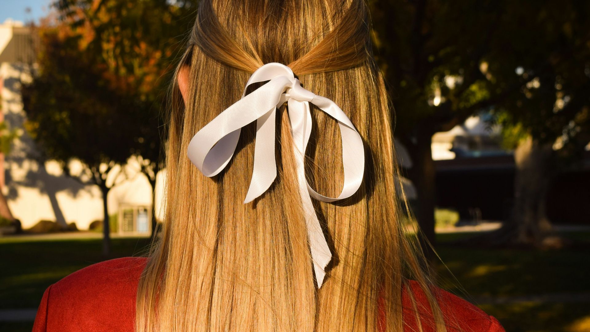 Woman's blonde hair with a white bow.