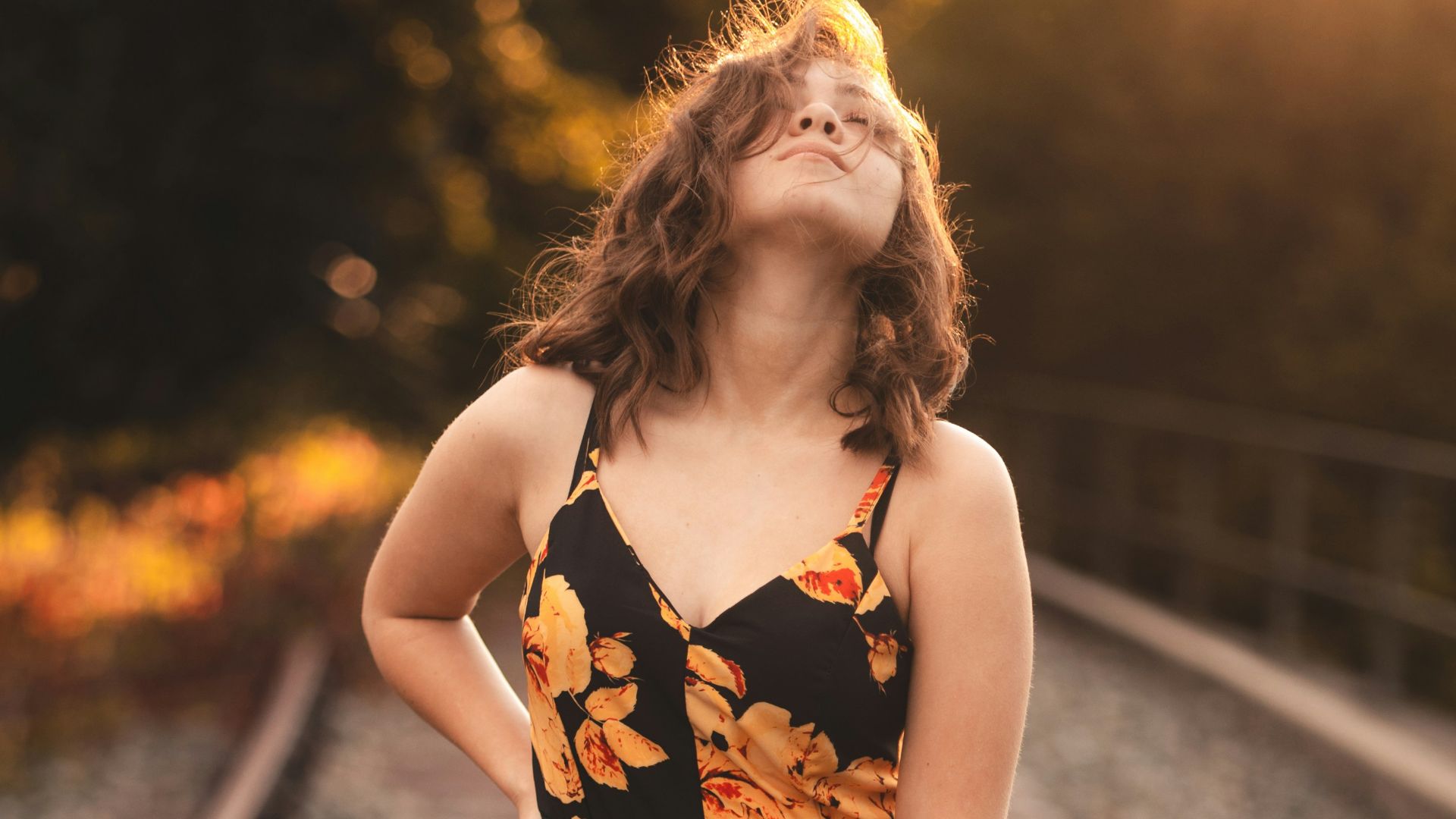 a woman in a dress standing on train tracks
