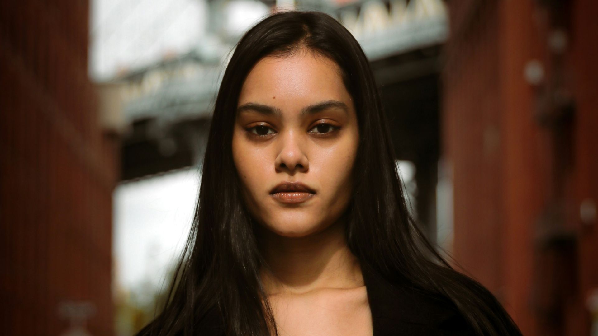 a woman with long hair standing in front of a bridge