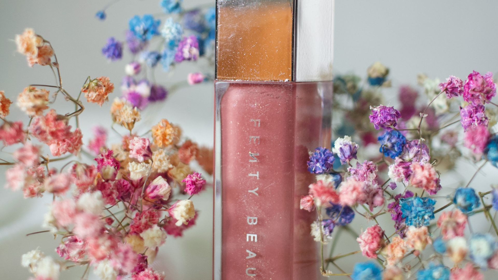 a bottle of liquid sitting next to a bunch of flowers