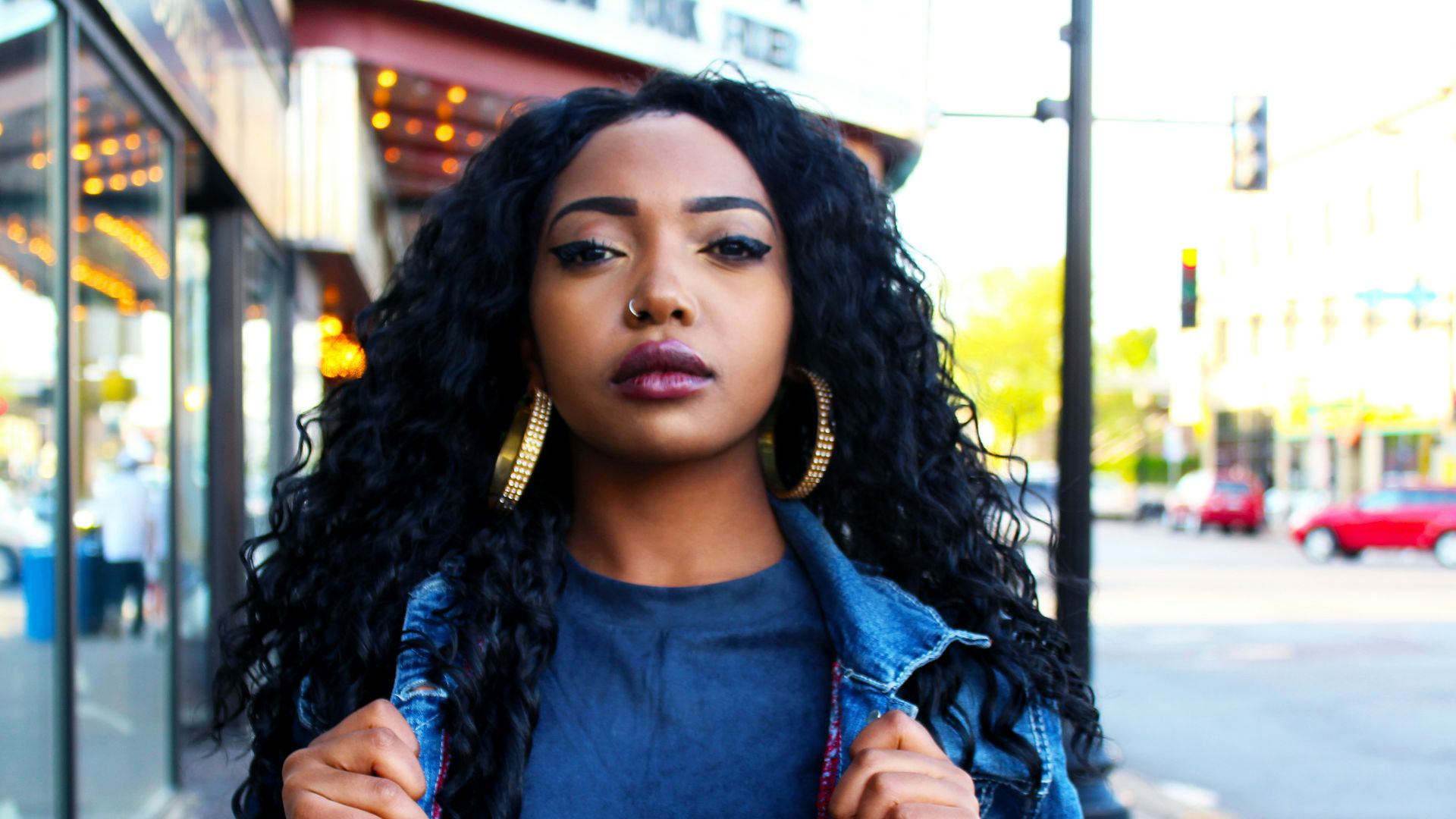 women holding denim jacket near glass window