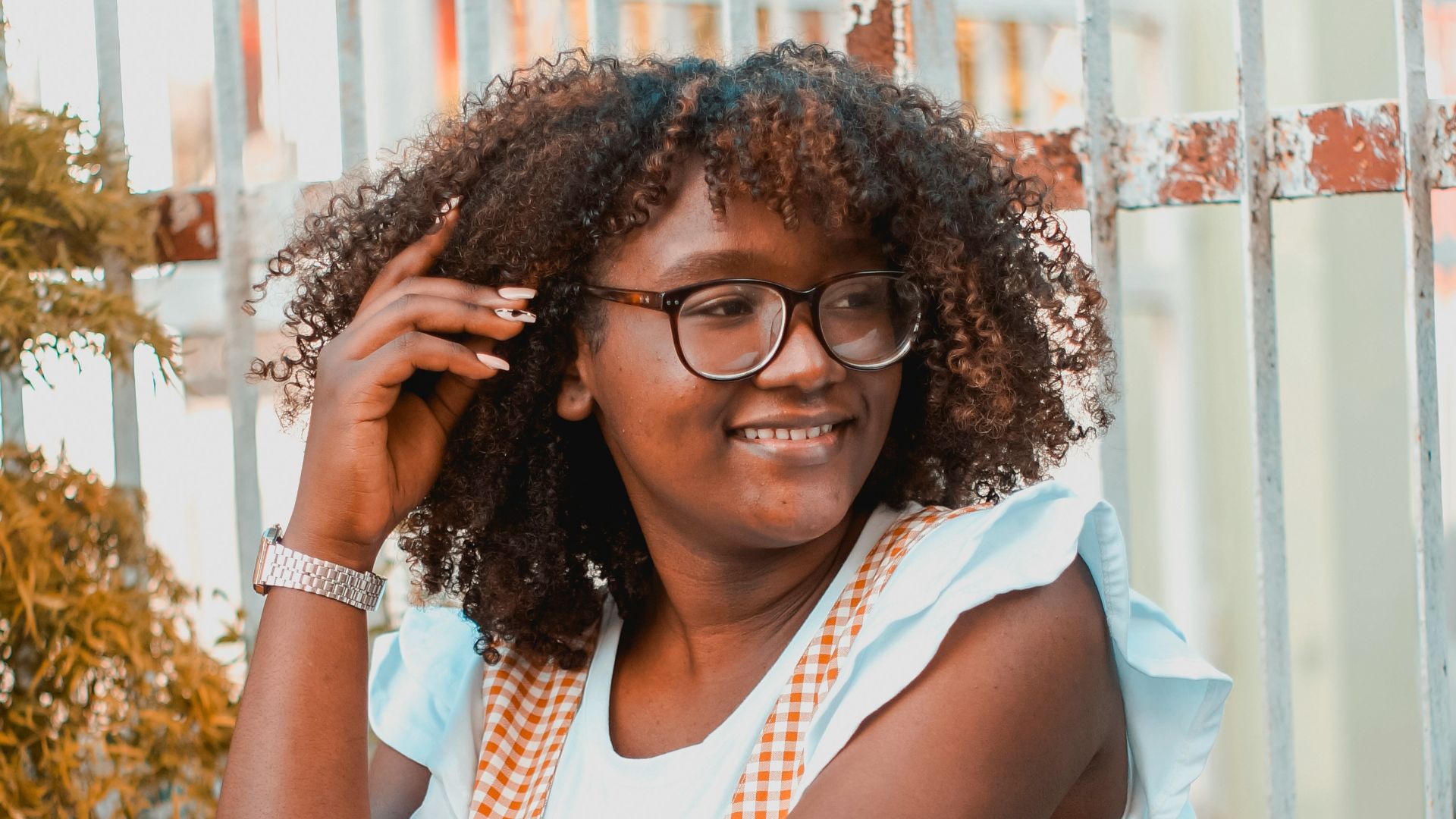 woman in white shirt and red and white checked skirt sitting on white chair