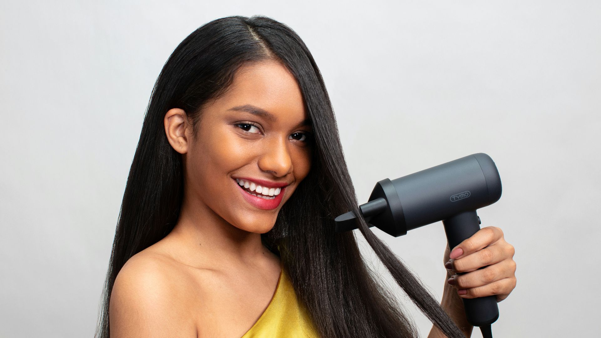 a woman holding a hair dryer and smiling
