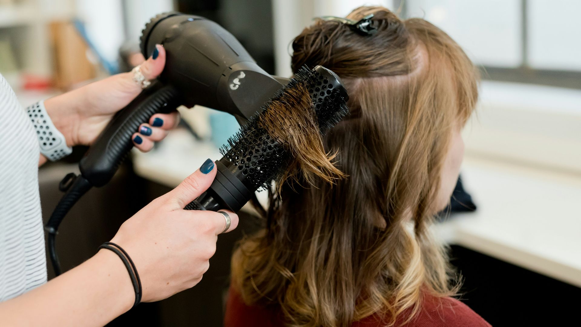 woman in red long sleeve shirt holding hair blower
