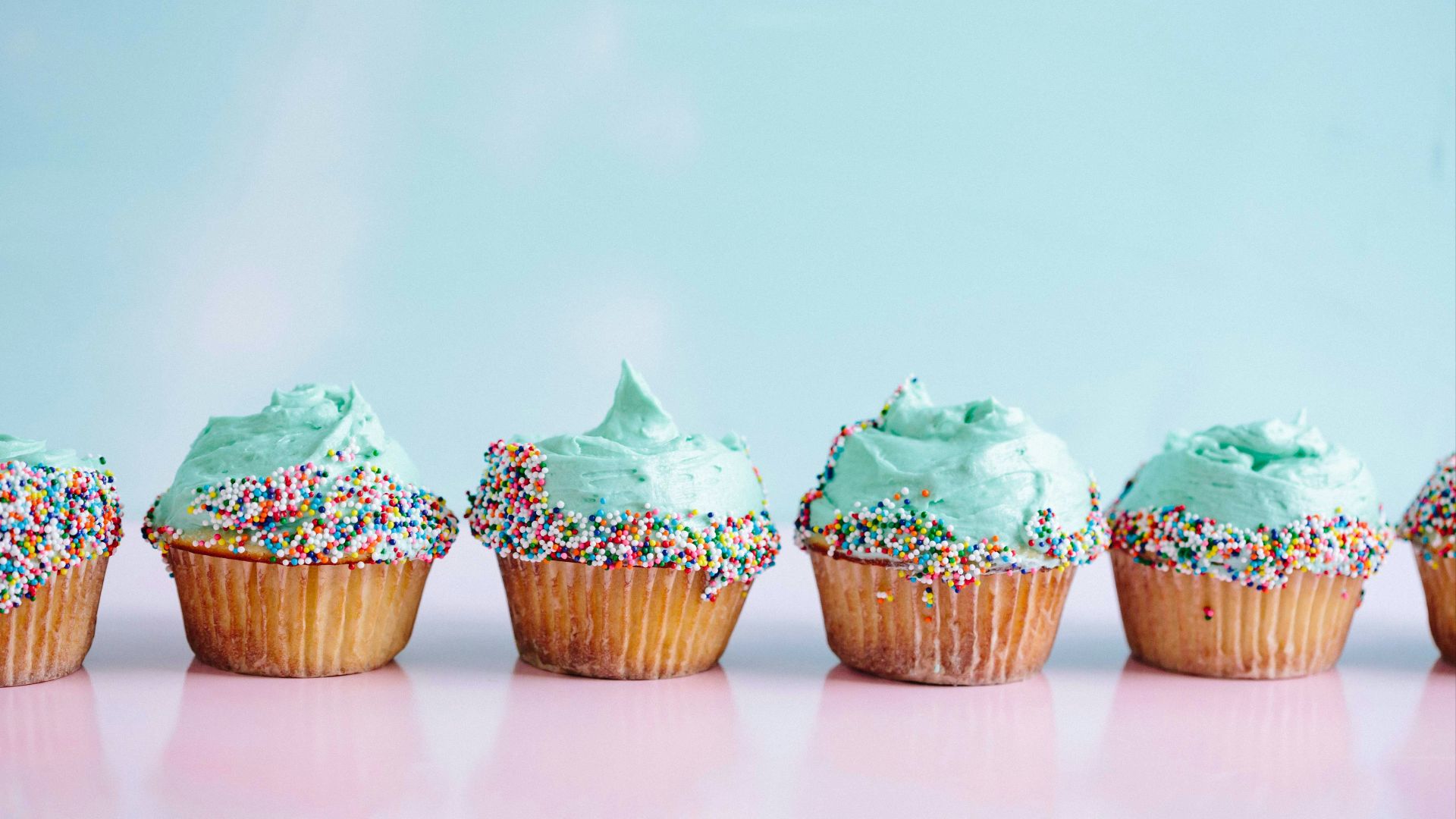 six teal icing cupcakes with sprinkles