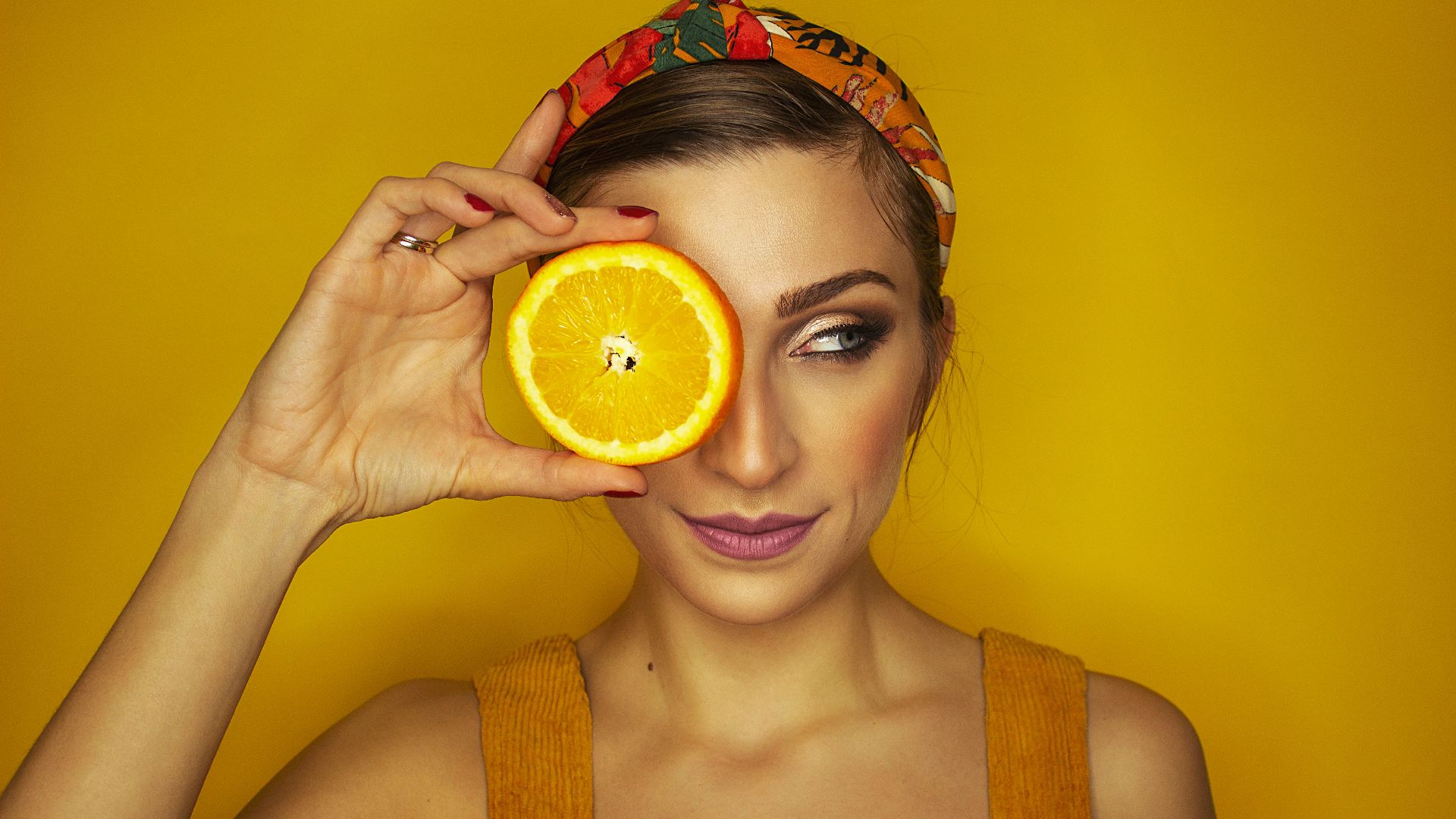 woman covering her right eye with orange slice