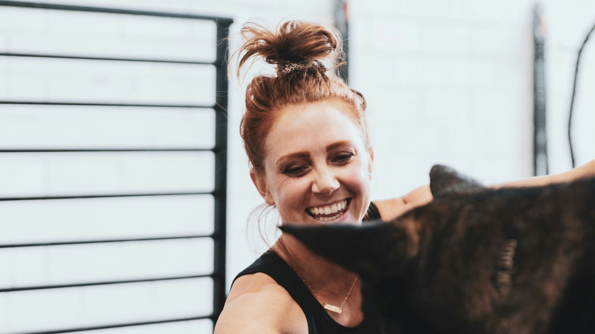 girl in pink t-shirt hugging black short coated dog