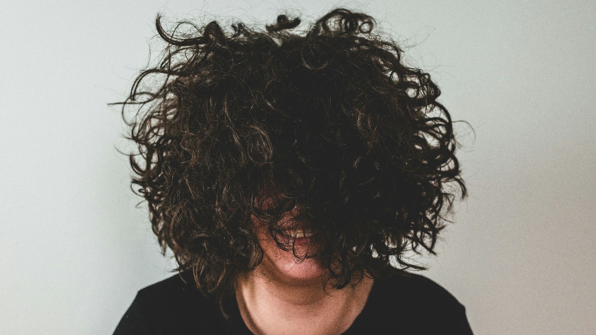 person with curly hair covering face