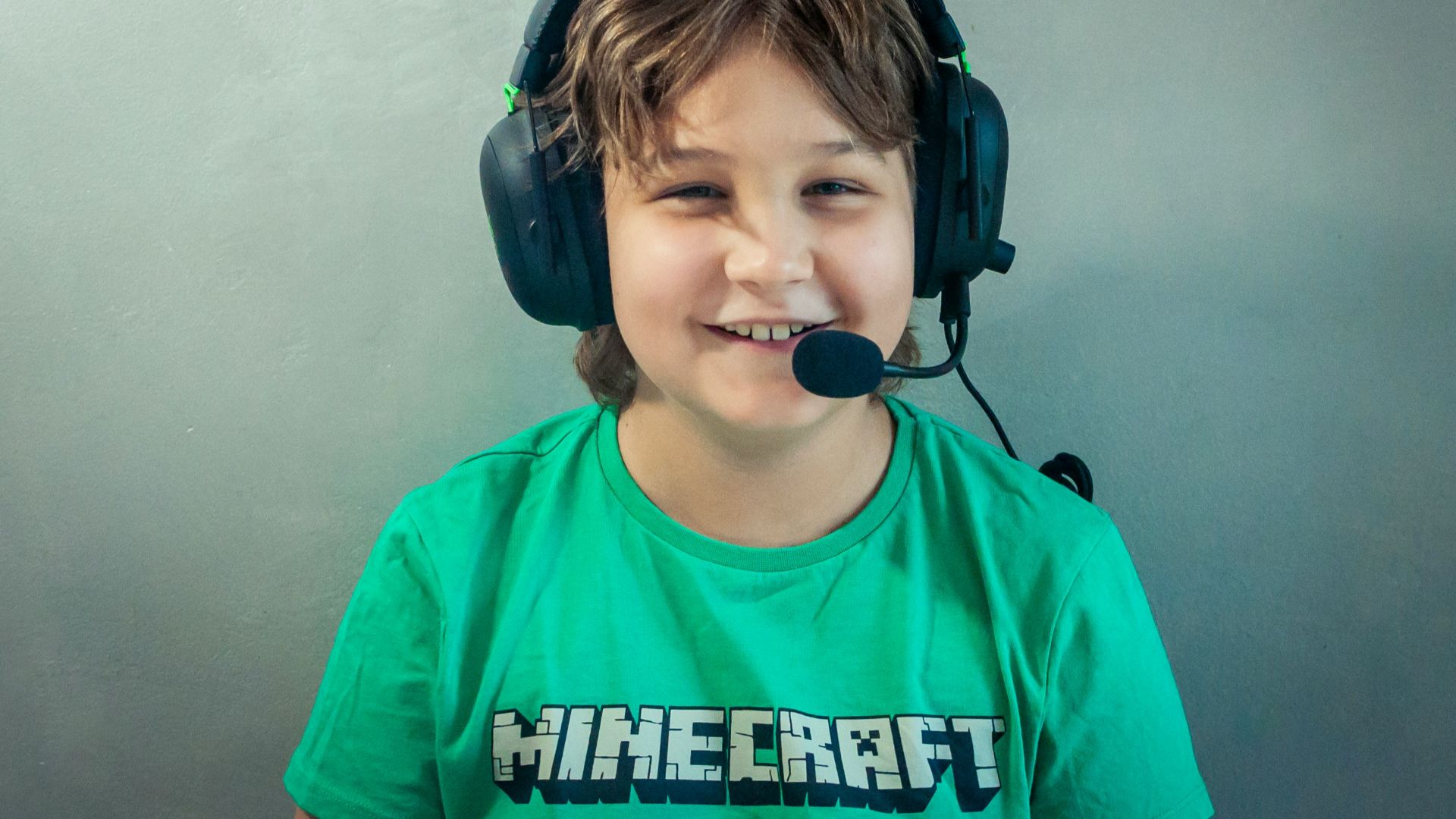 A young boy wearing headphones and a green shirt
