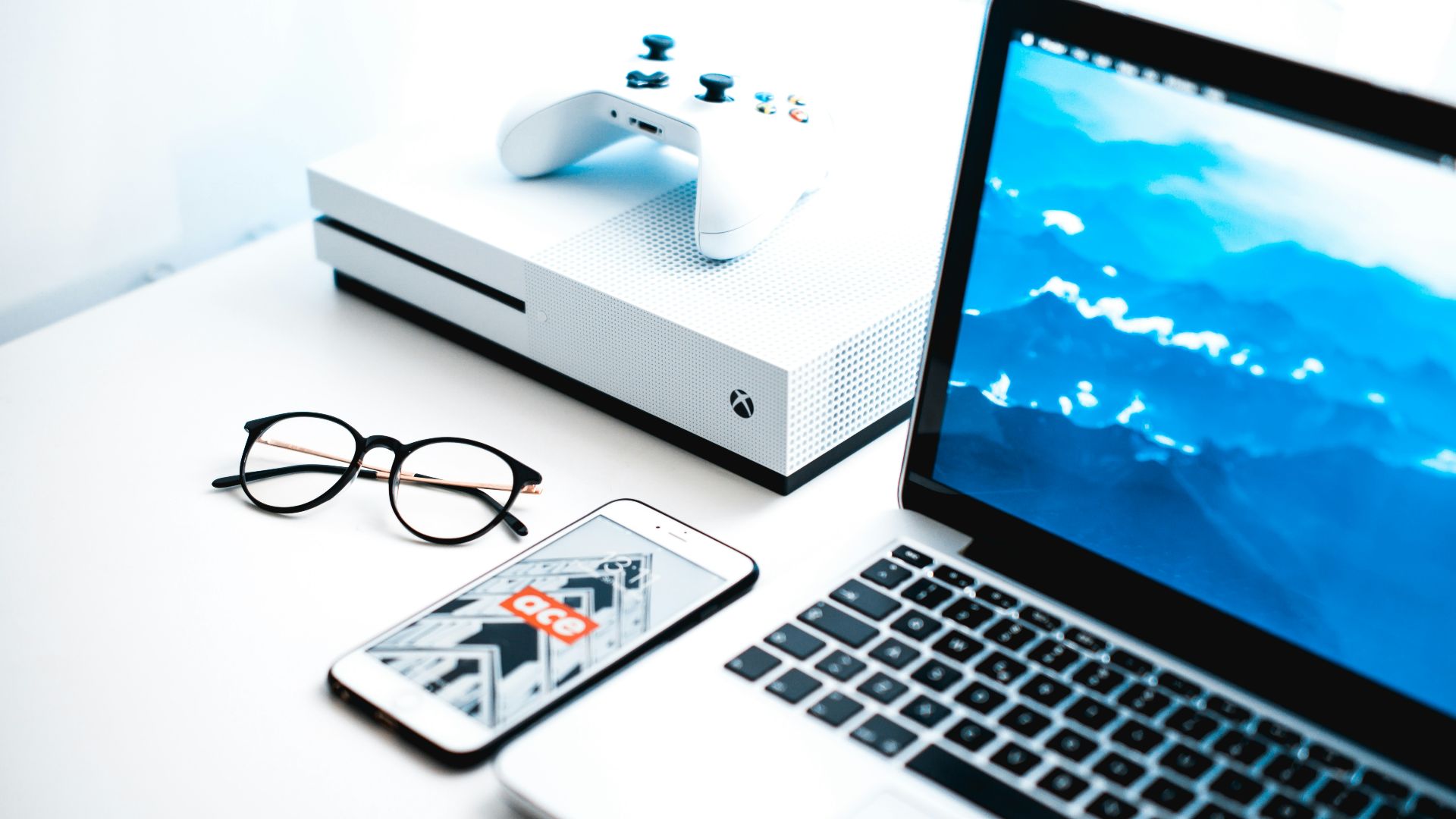 turned on MacBook Pro beside iPhone and Xbox One Slim