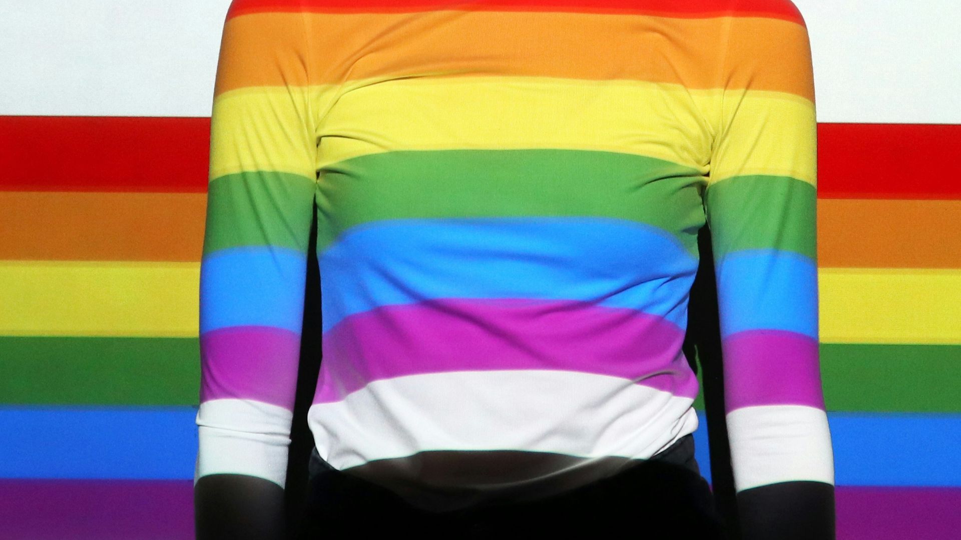 a woman standing in front of a rainbow colored wall