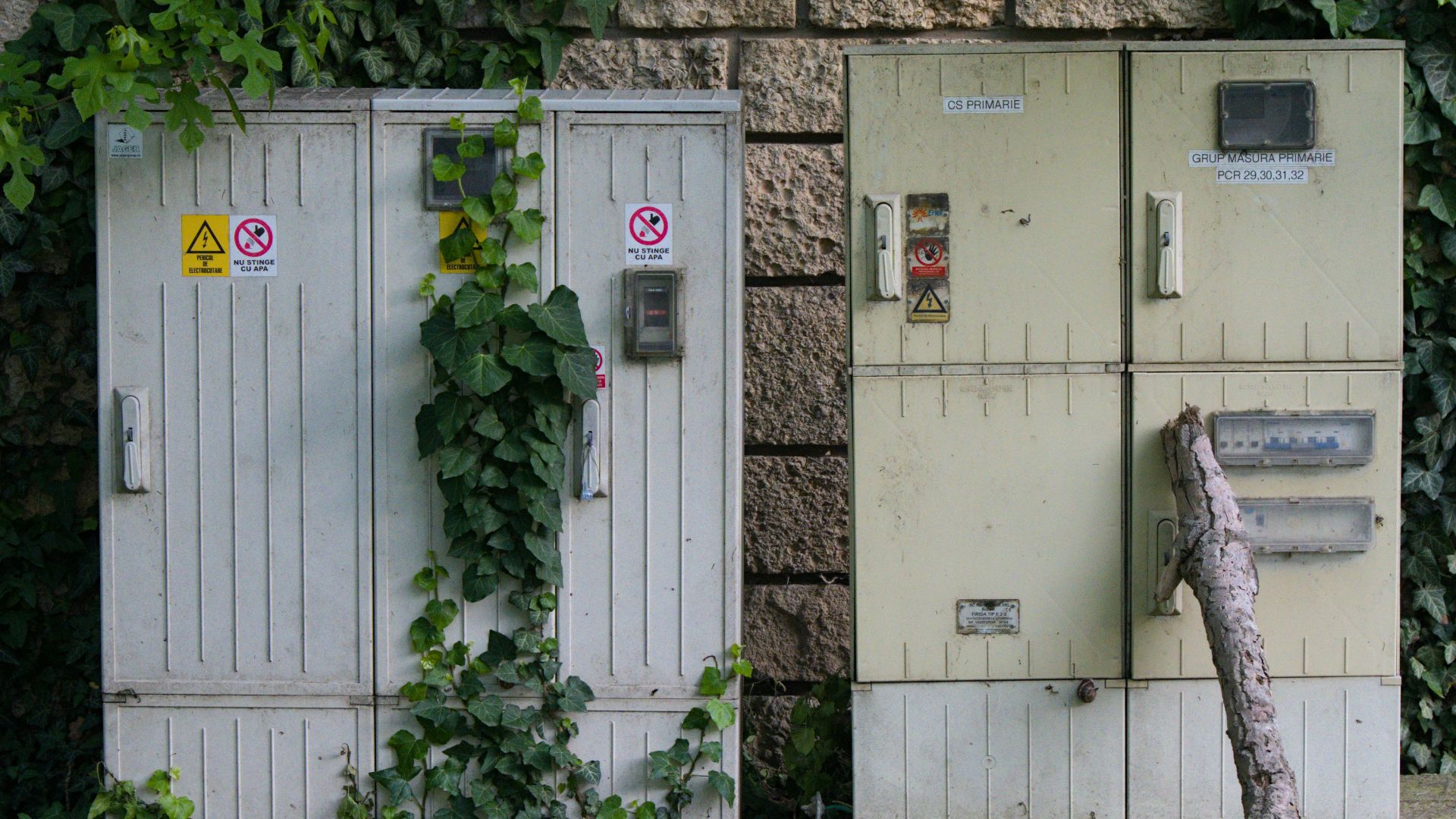 a couple of old electrical boxes sitting next to a brick wall