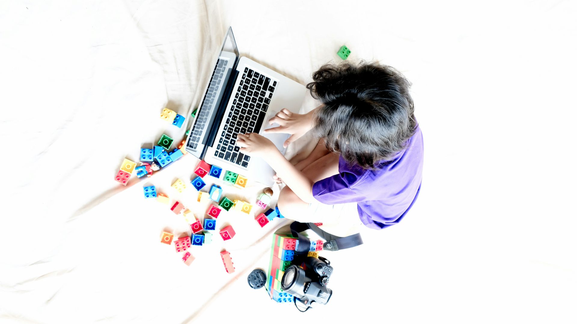 a person sitting on a bed using a laptop