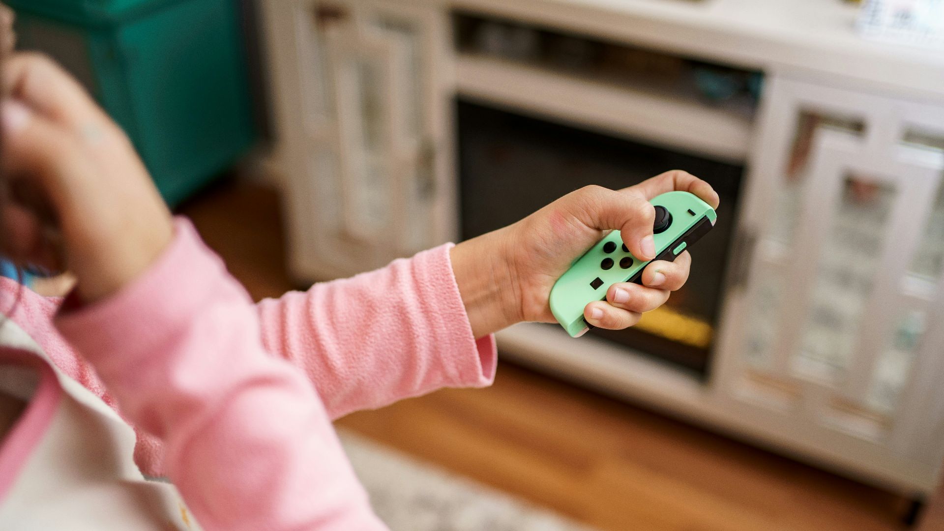 child in pink long sleeve shirt holding green and white plastic toy