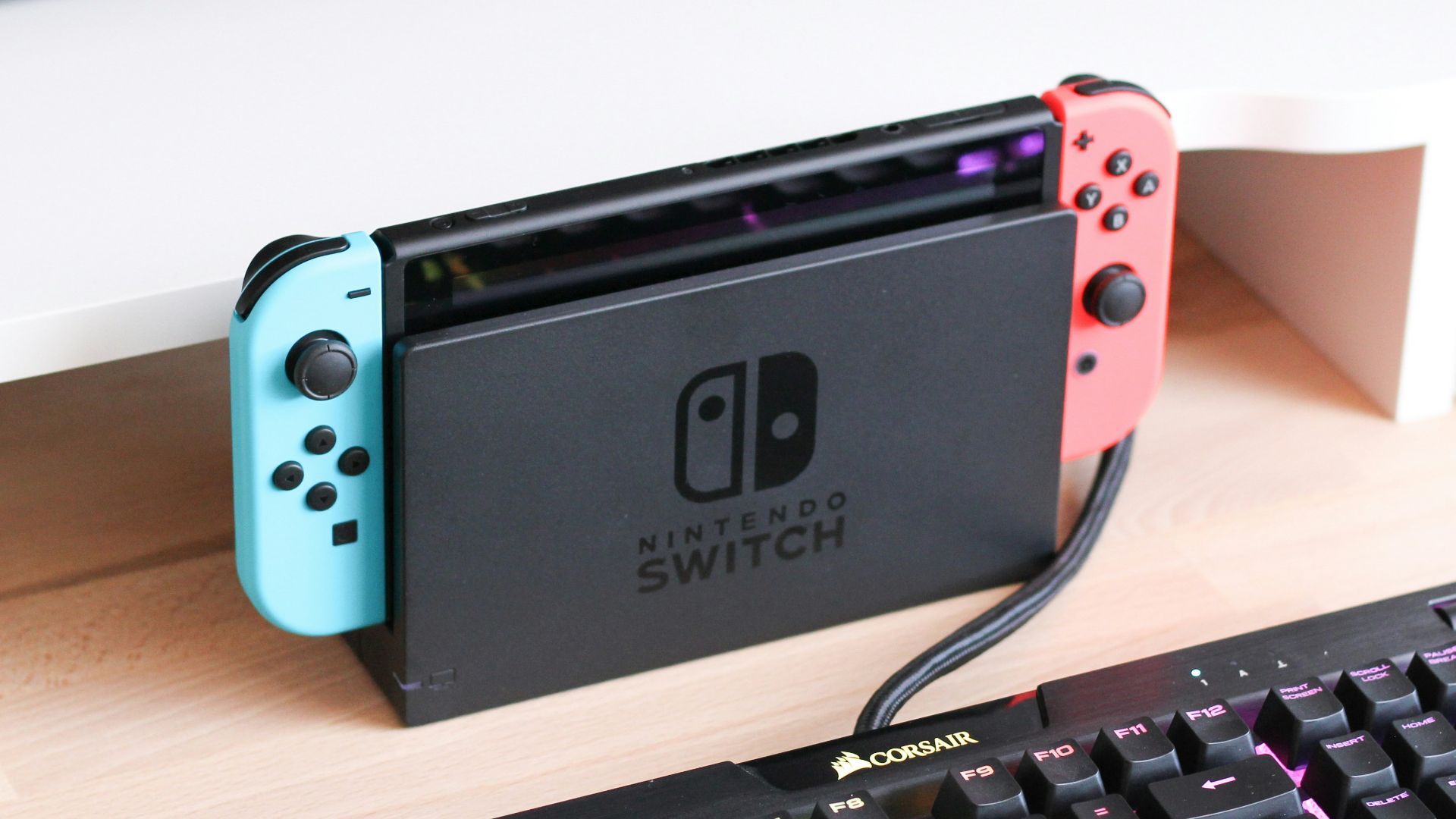 a nintendo switch sitting on a desk next to a keyboard