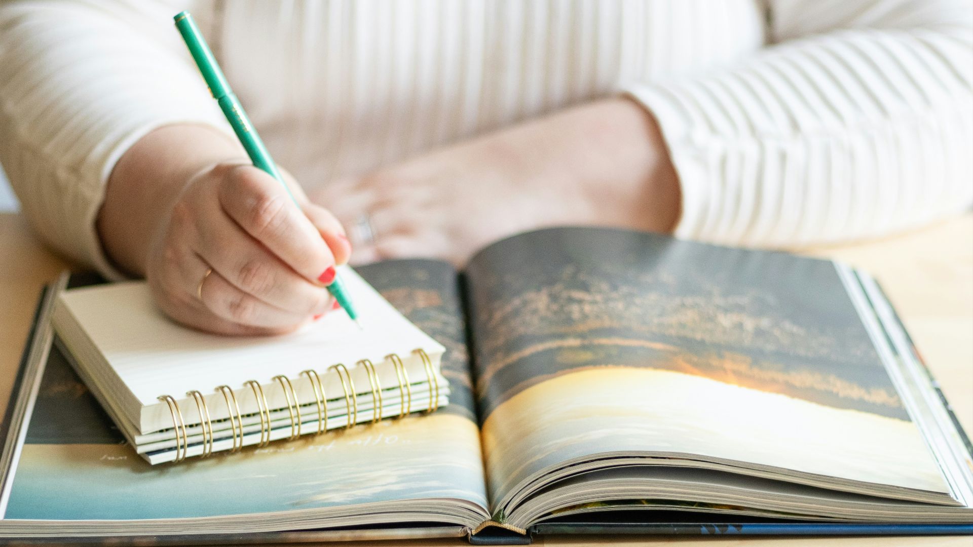 a person writing on a book with a pen