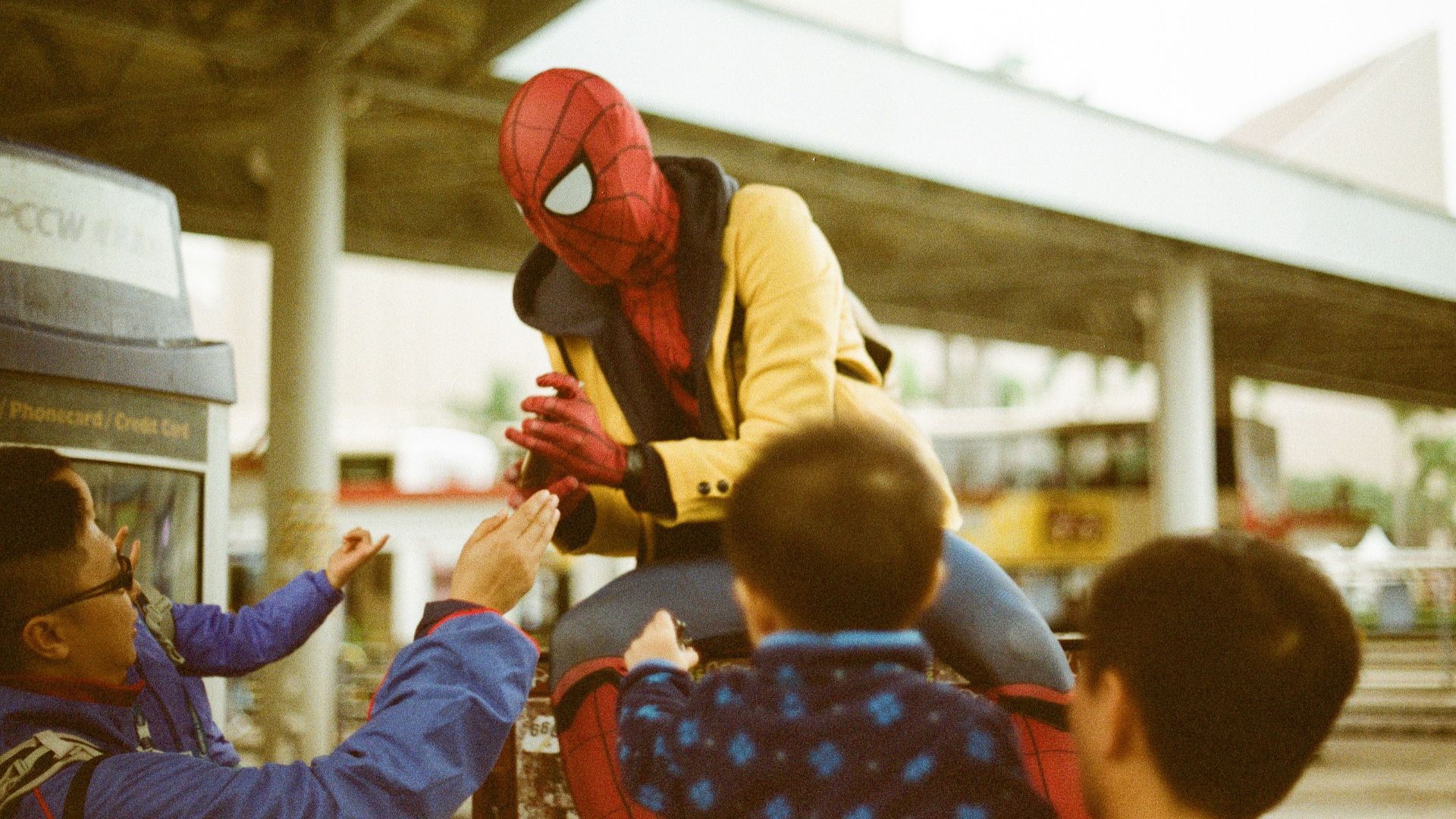 a man in a spider man costume is handing something to a child