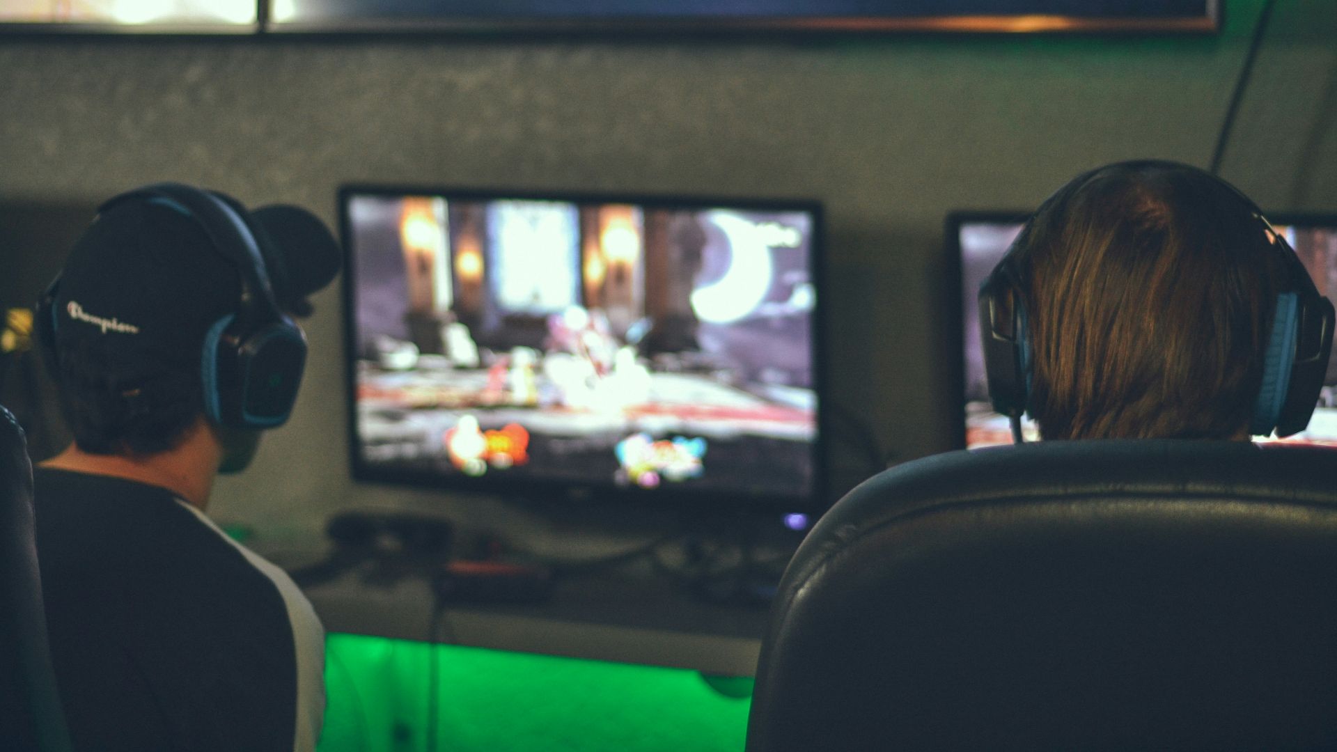 selective focus photography of two persons playing game in front of monitors
