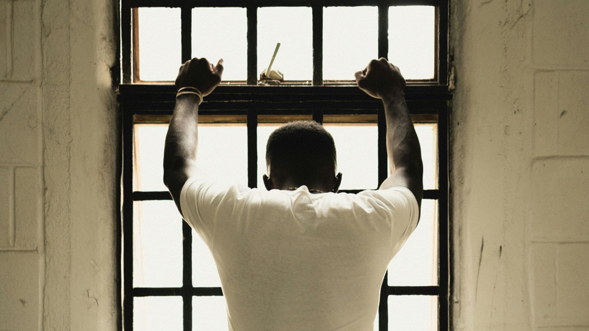 man in white t-shirt standing in front of window