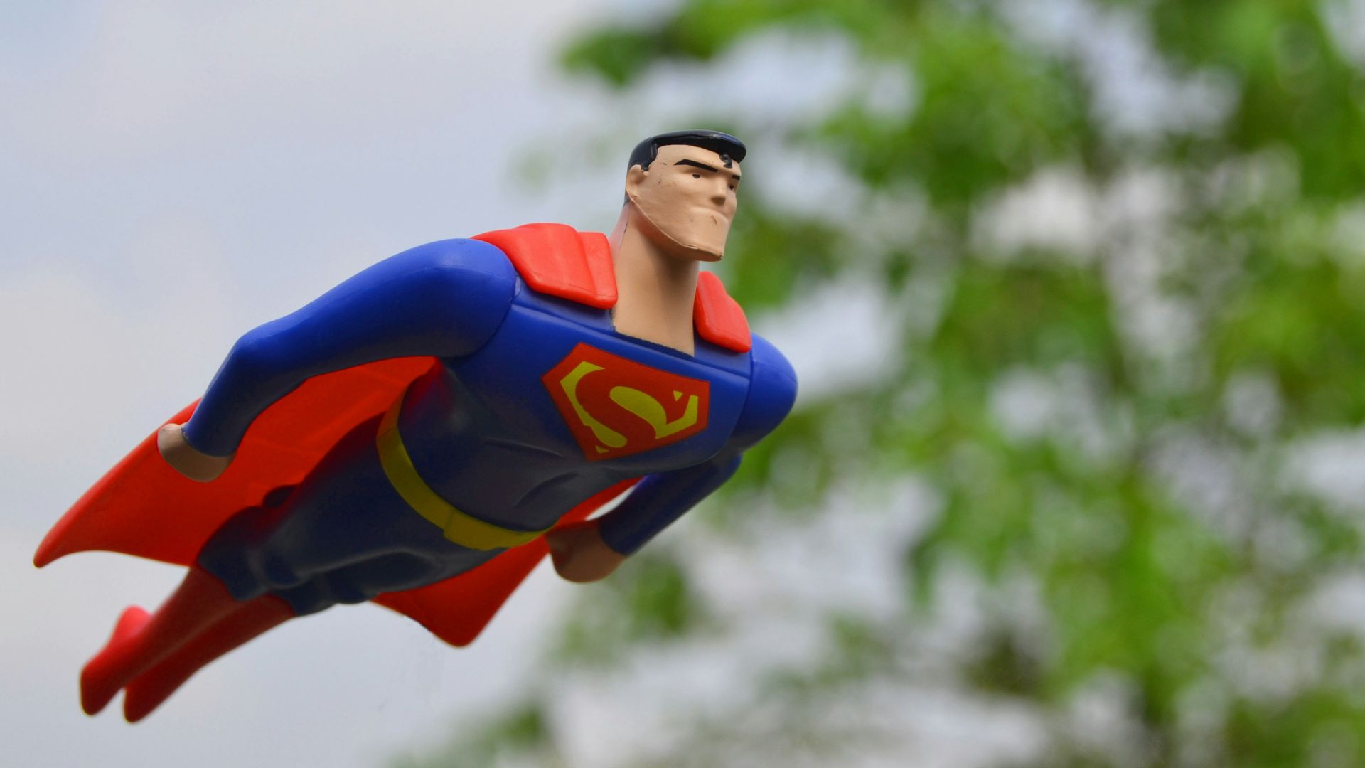 Superman flying near green grass