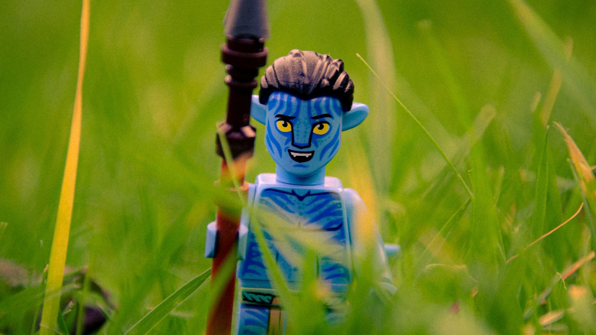 a toy is sitting in the grass with a toy gun