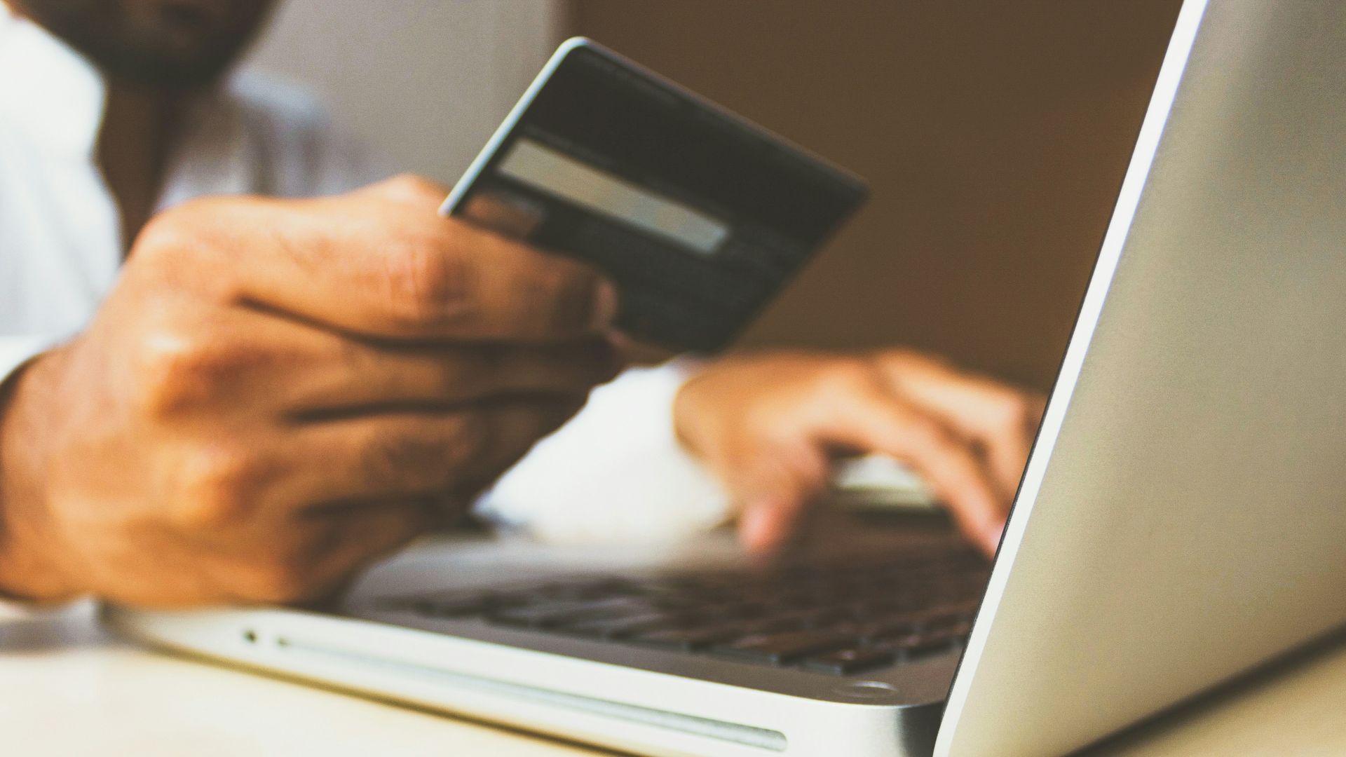 person using laptop computer holding card