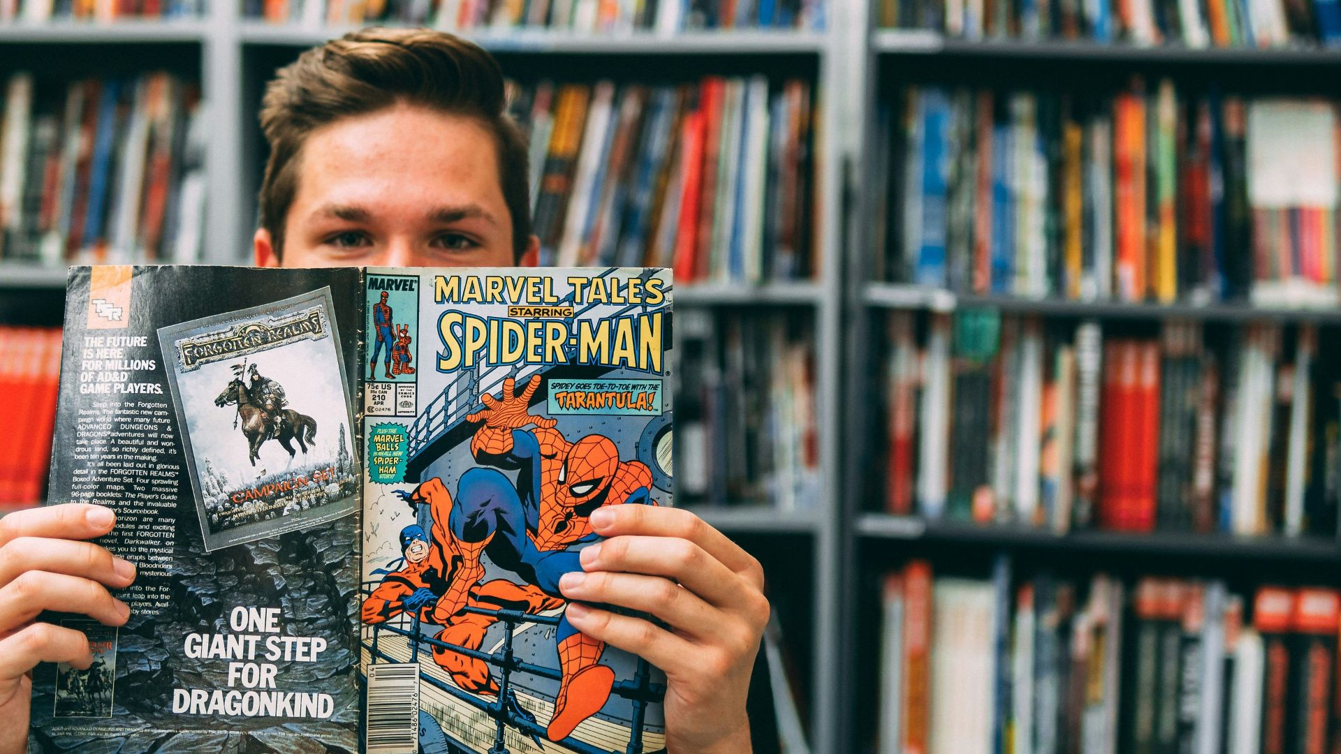 A man holding up a book in front of a library full of books