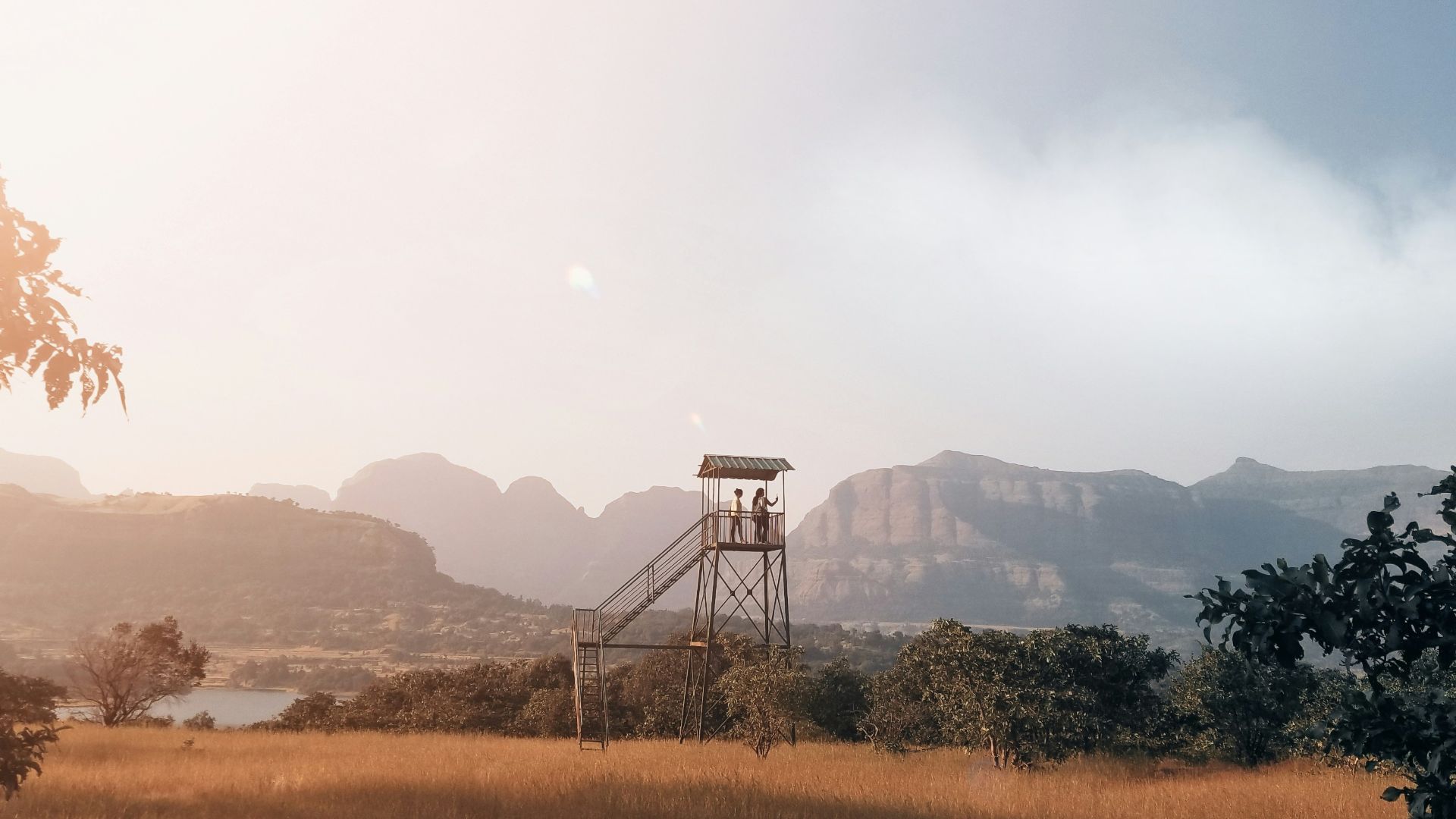 a field with a water tower and mountains in the background