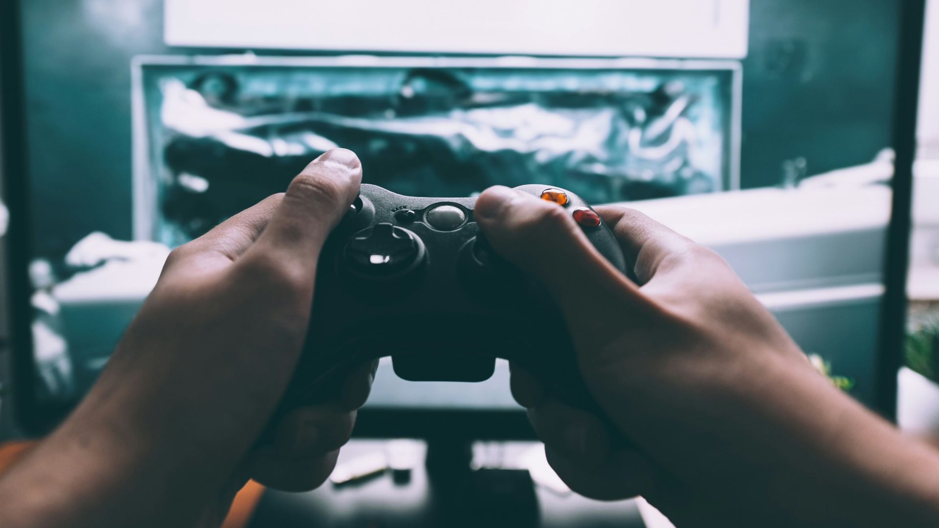 person holding game controller in-front of television