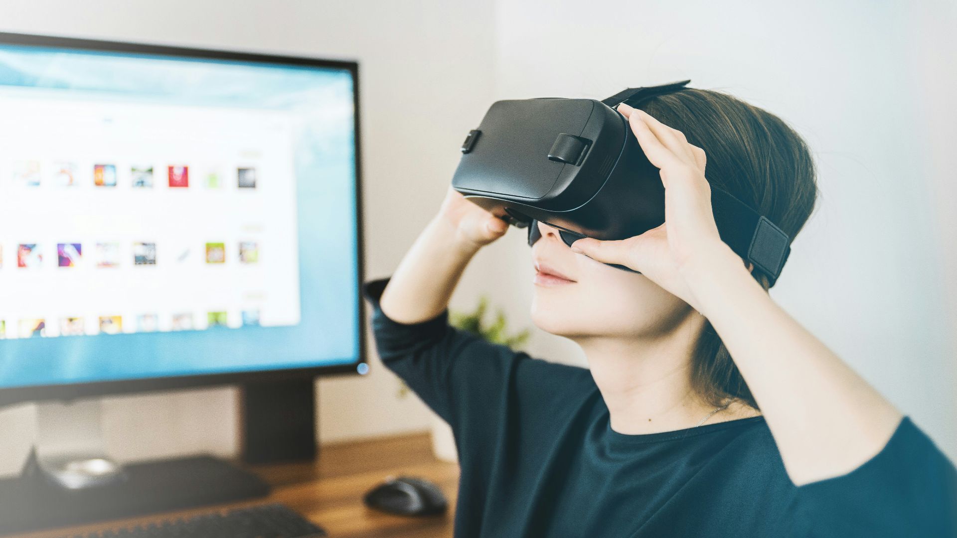 woman using black VR headset beside computer
