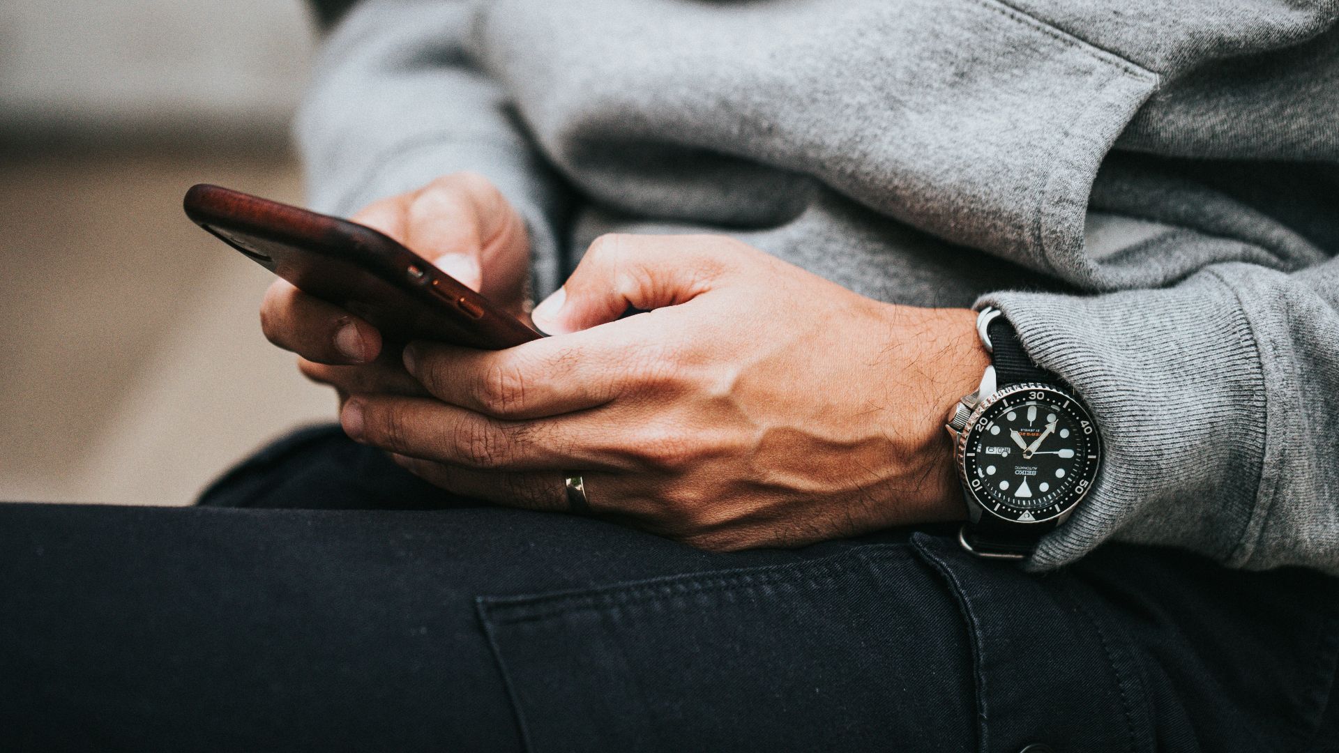person in gray sweater wearing black and silver chronograph watch