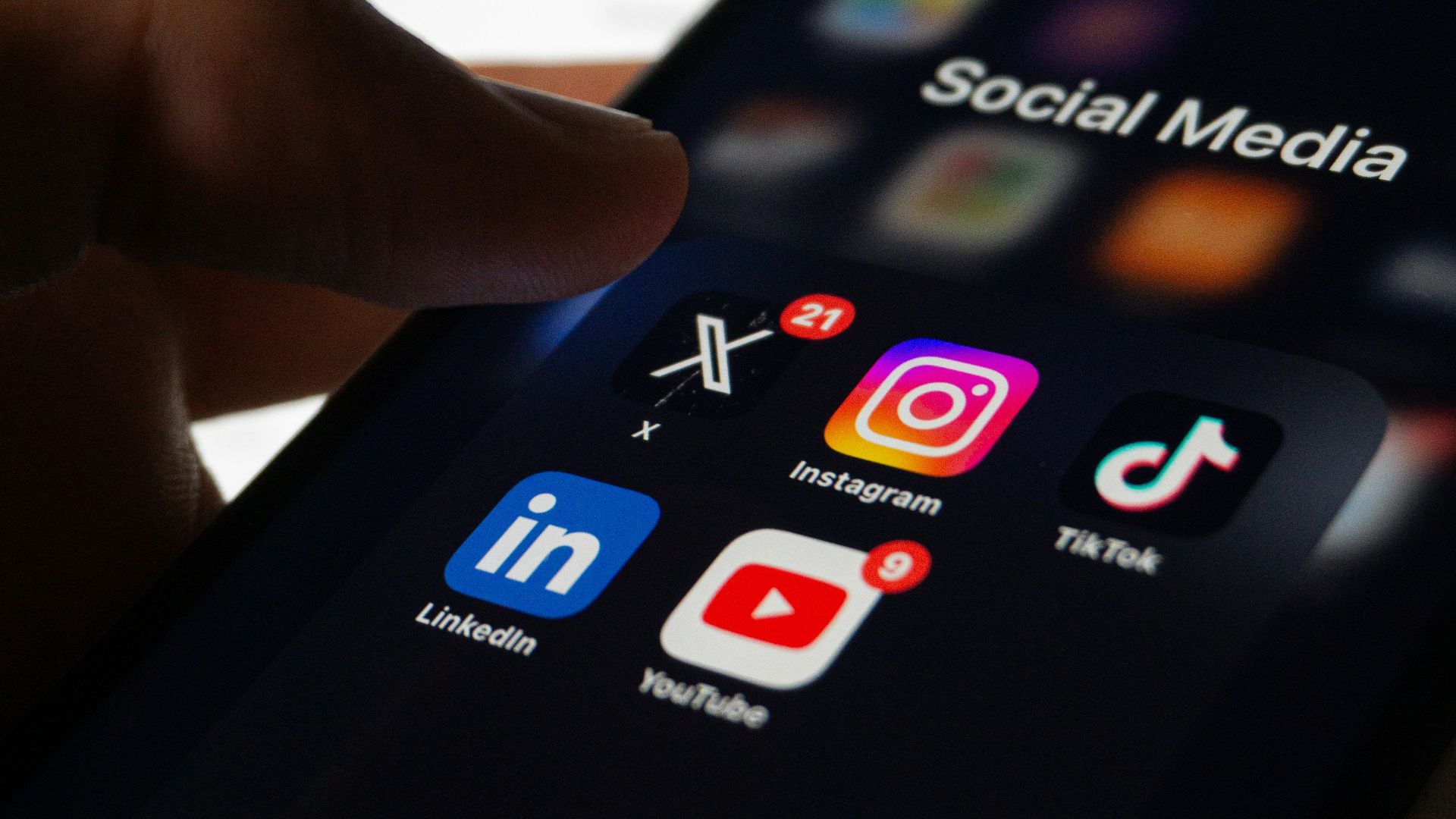 A person holding a smart phone with social media on the screen