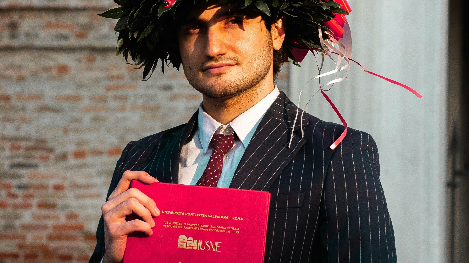 man in black suit holding red book