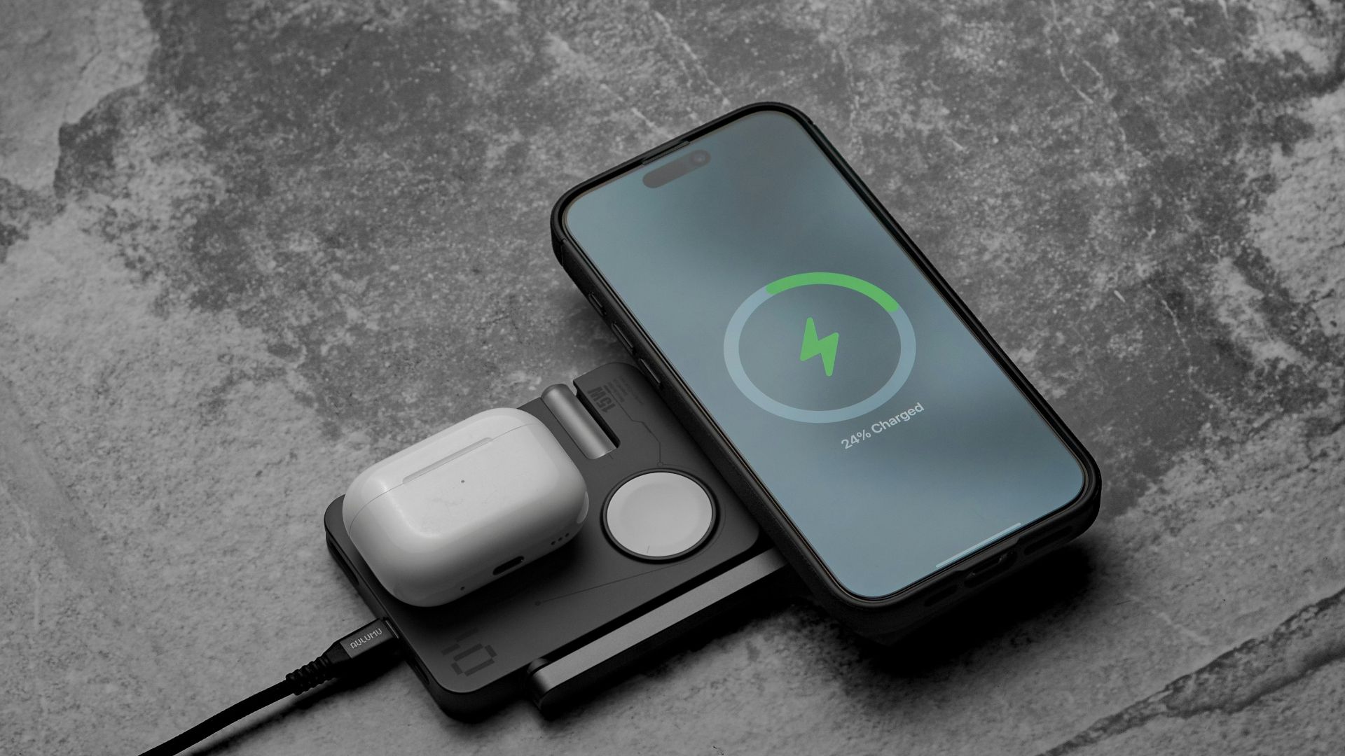 Phone, watch, and earbuds charging on a pad.